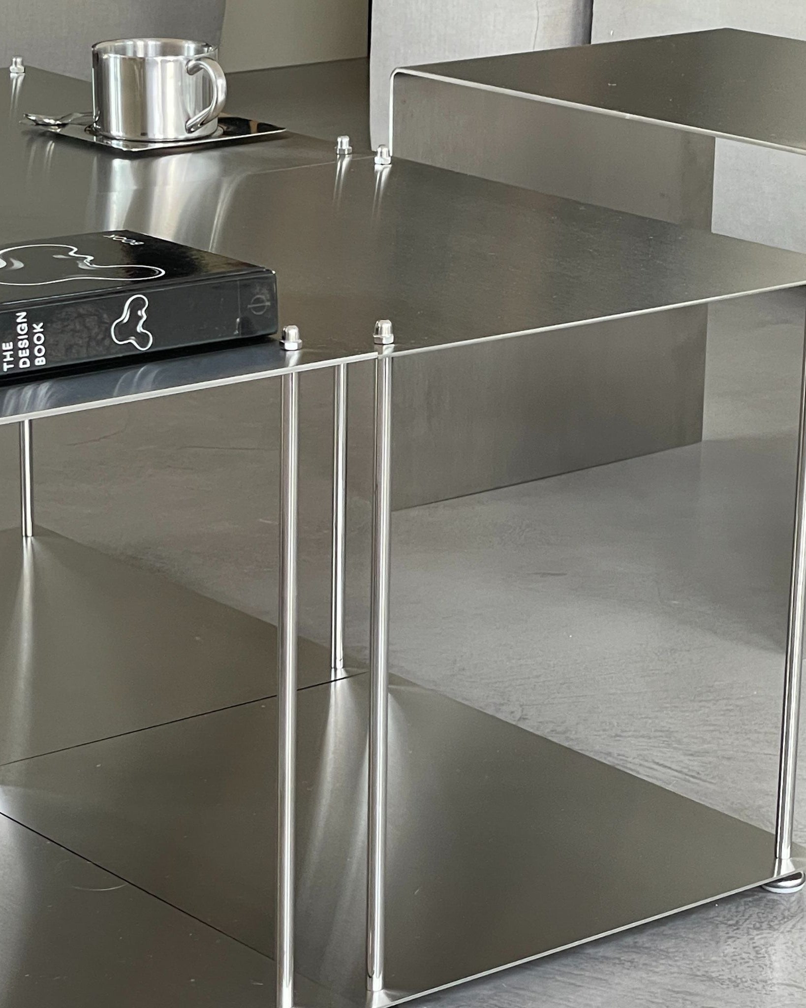 Auschnitt von vier quadratische Modulum-Module aus gebürstetem Edelstahl, kombiniert zu einem modernen Couchtisch im Wohnzimmer