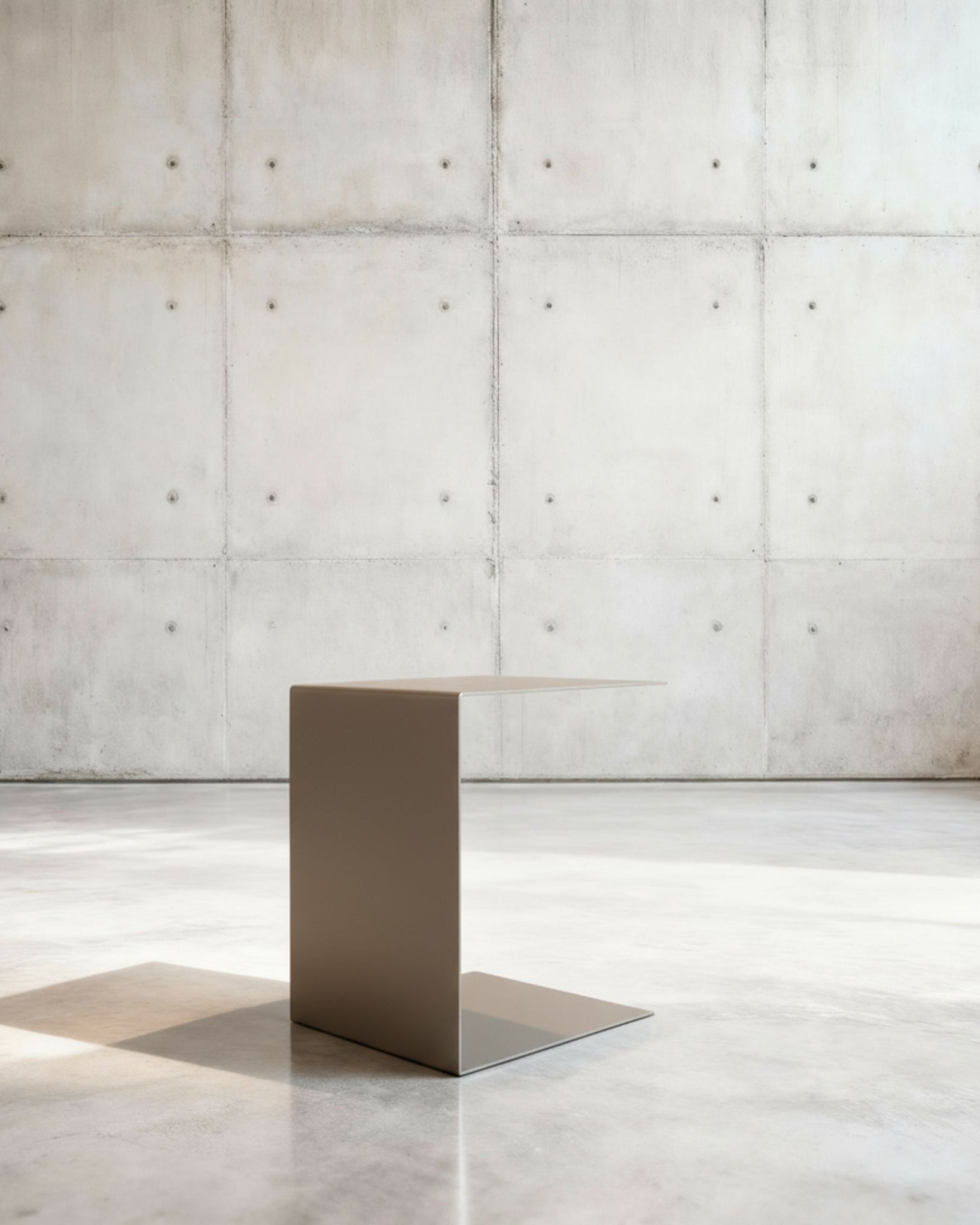 Minimalistischer Beistelltisch BIG C aus graubeige matt lackiertem Stahl in architektonischem Raum auf Betonboden