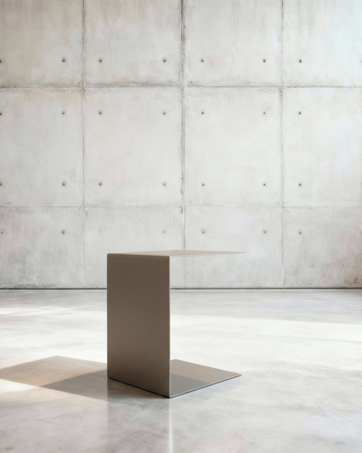 Minimalistischer Beistelltisch BIG C aus graubeige matt lackiertem Stahl in architektonischem Raum auf Betonboden