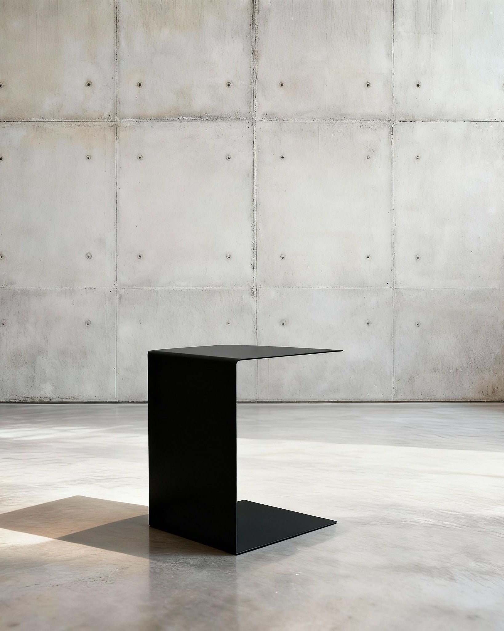 Minimalistischer Beistelltisch BIG C aus schwarz matt lackiertem Stahl in architektonischem Raum auf Betonboden