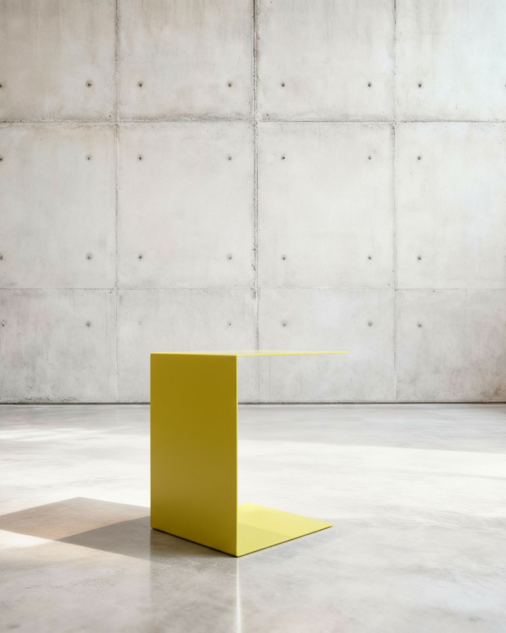 Minimalistischer Beistelltisch BIG C aus schwefelgelb matt lackiertem Stahl in architektonischem Raum auf Betonboden