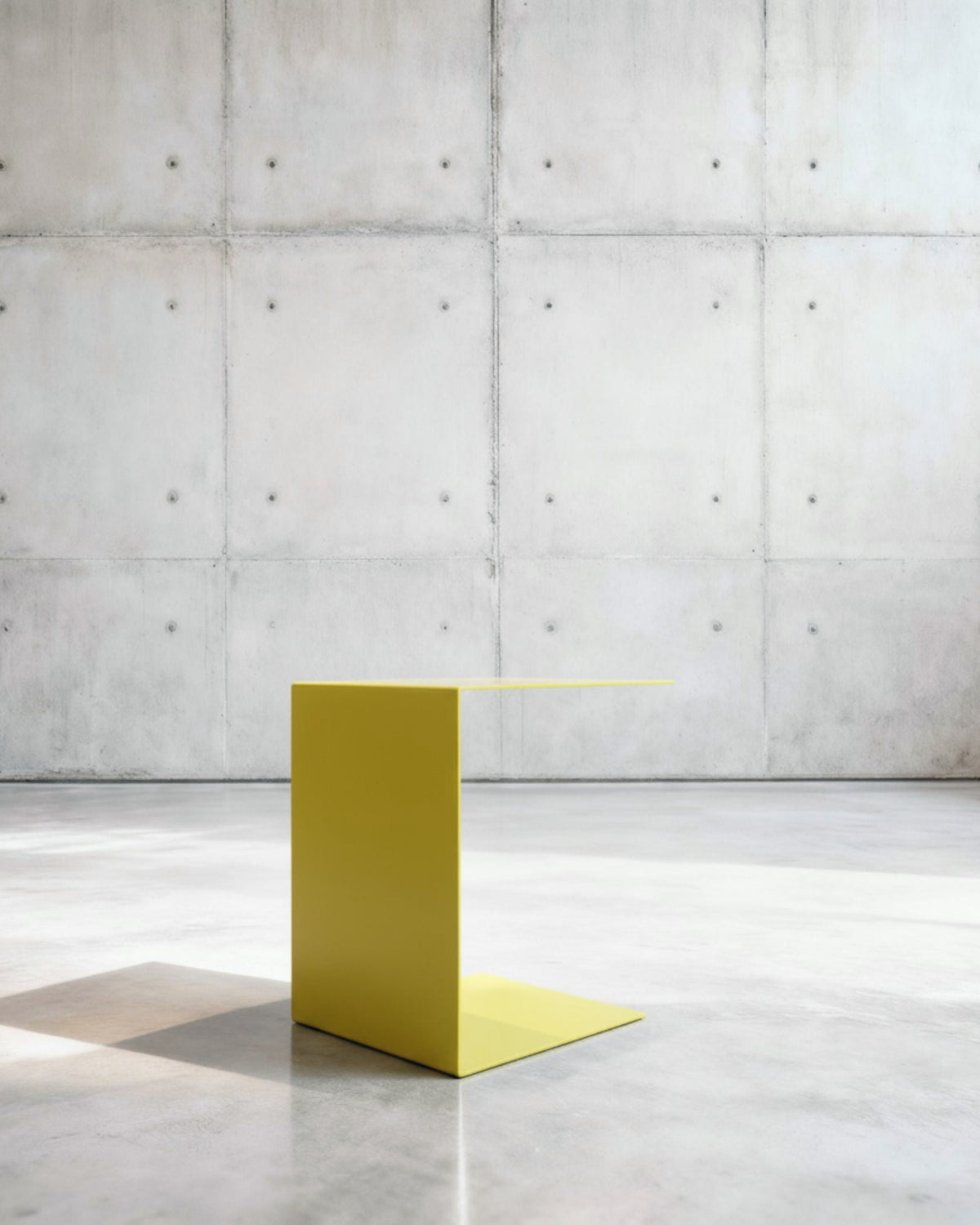 Minimalistischer Beistelltisch BIG C aus schwefelgelb matt lackiertem Stahl in architektonischem Raum auf Betonboden