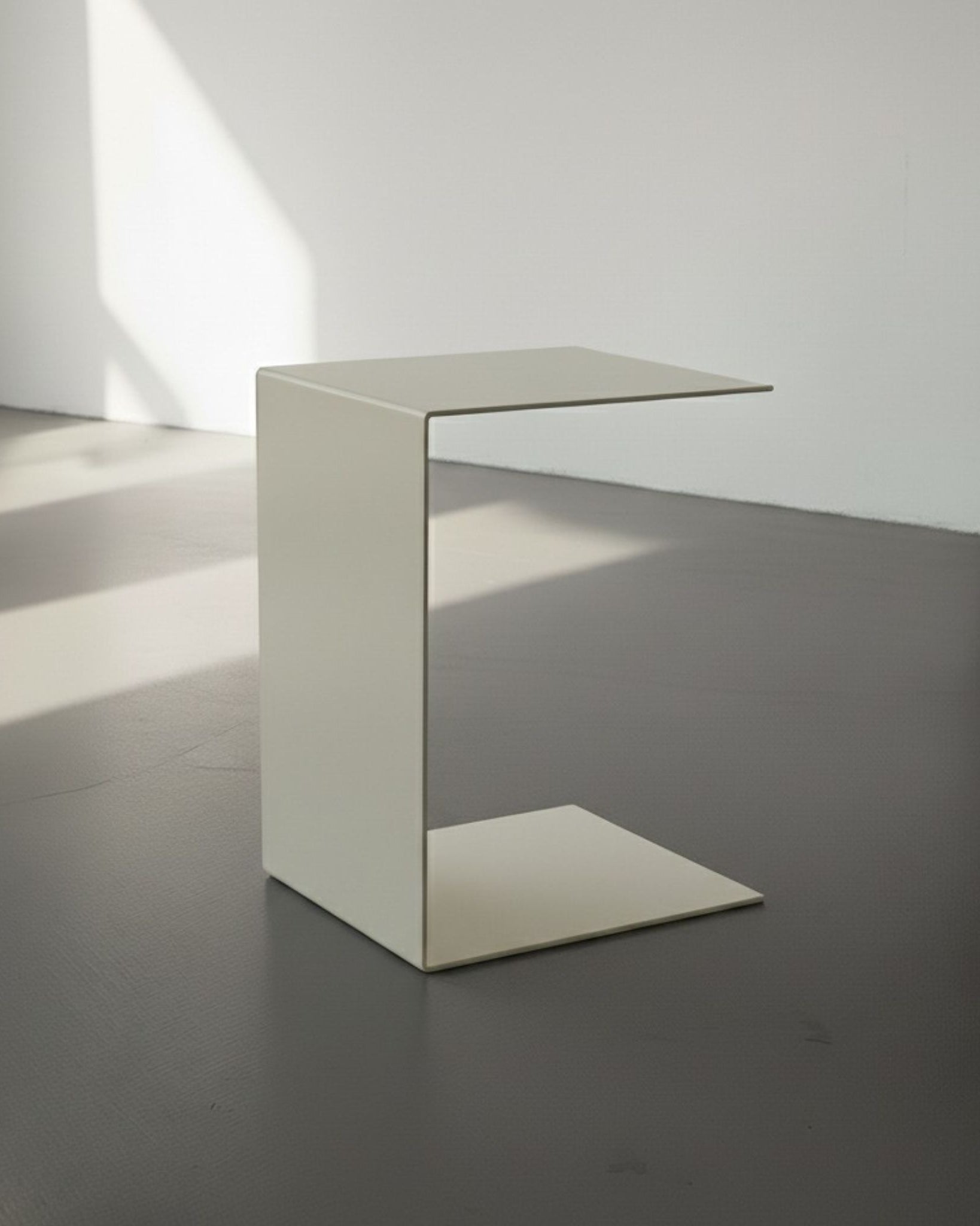 BIG C in cremeweiß auf grauen Betonboden vor weißer Wand und Lichtspiel