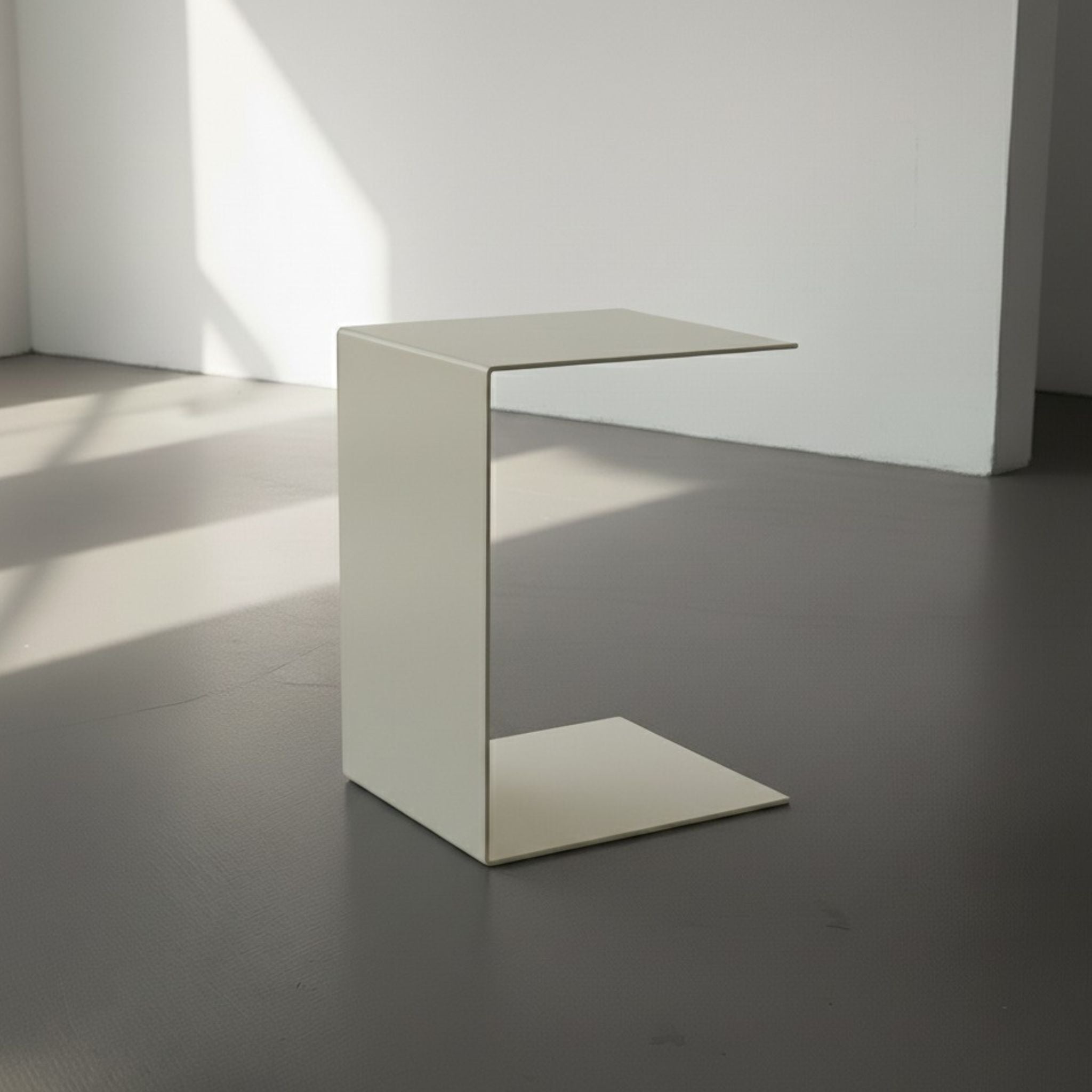 BIG C in cremeweiß auf grauen Betonboden vor weißer Wand und Lichtspiel