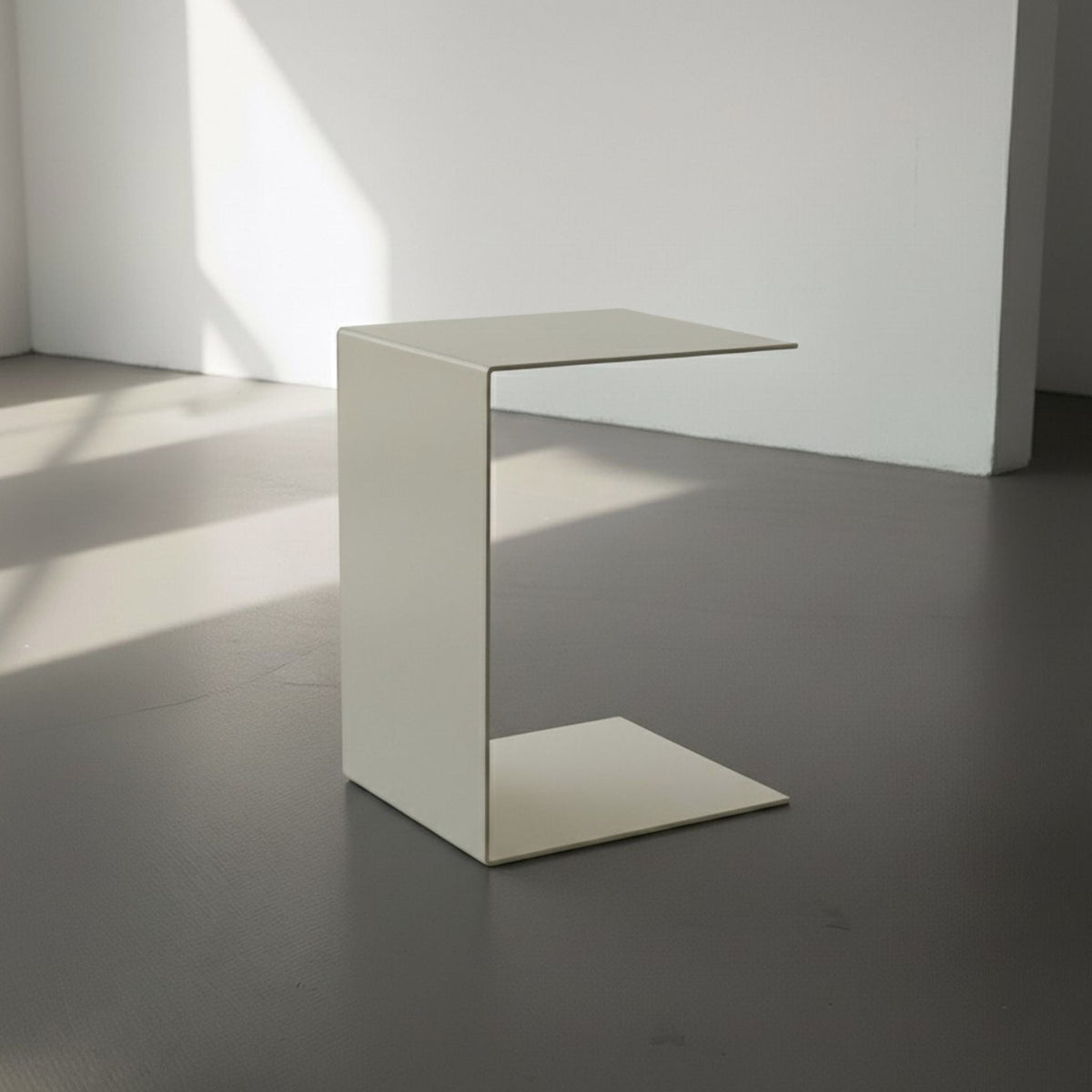 BIG C in cremeweiß auf grauen Betonboden vor weißer Wand und Lichtspiel