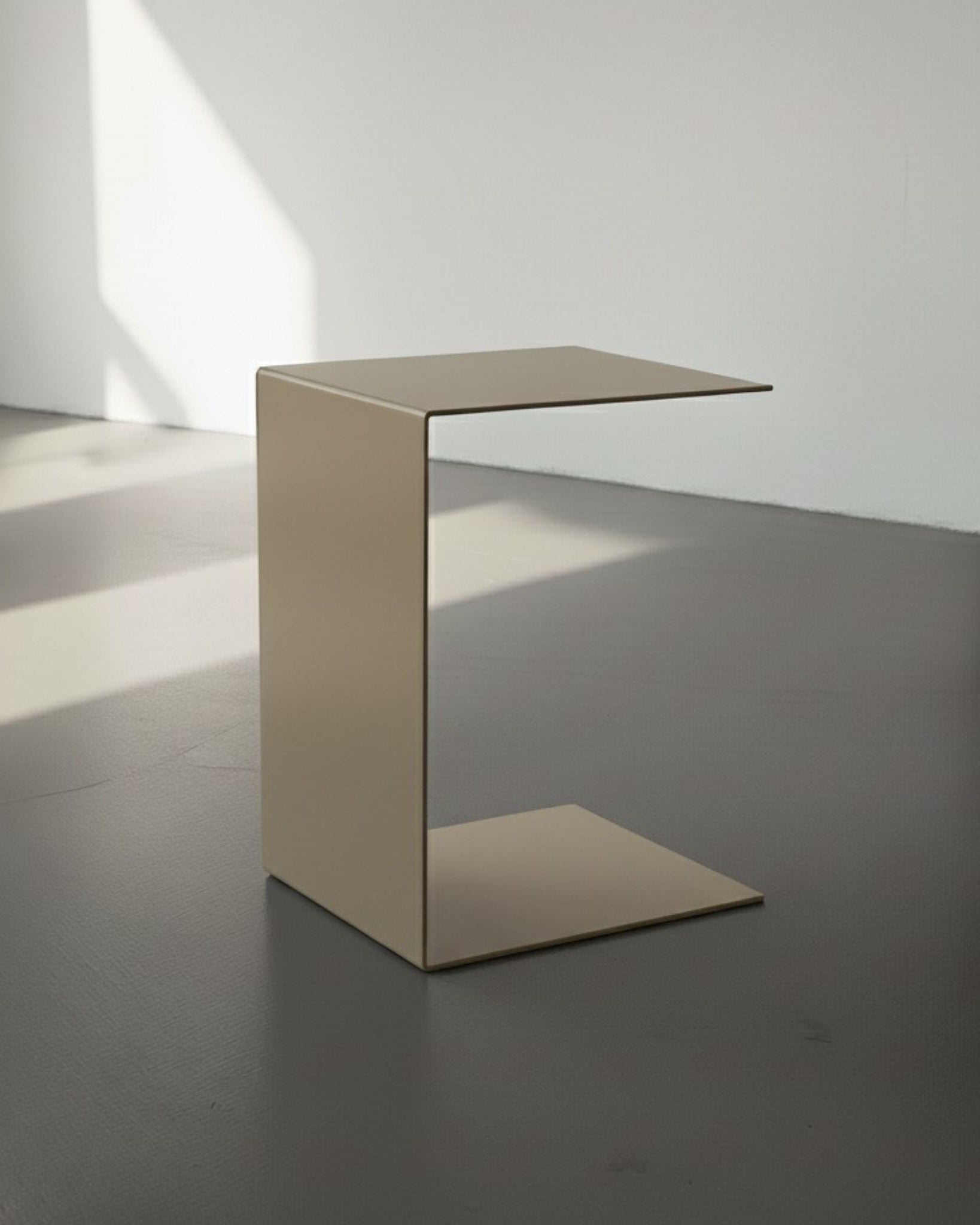 BIG C in graubeige auf grauen Betonboden vor weißer Wand und Lichtspiel