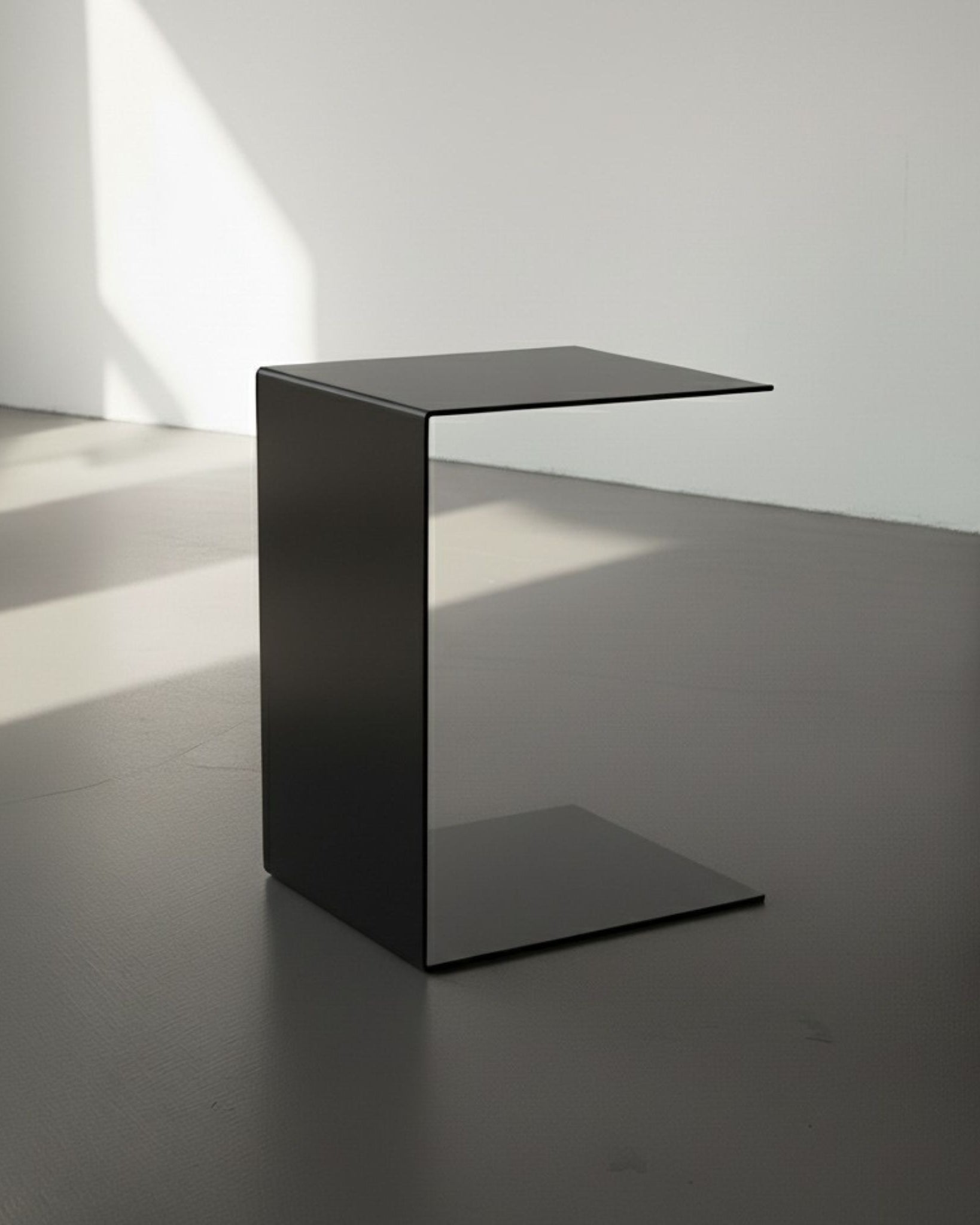 BIG C in schwarz auf grauen Betonboden vor weißer Wand und Lichtspiel