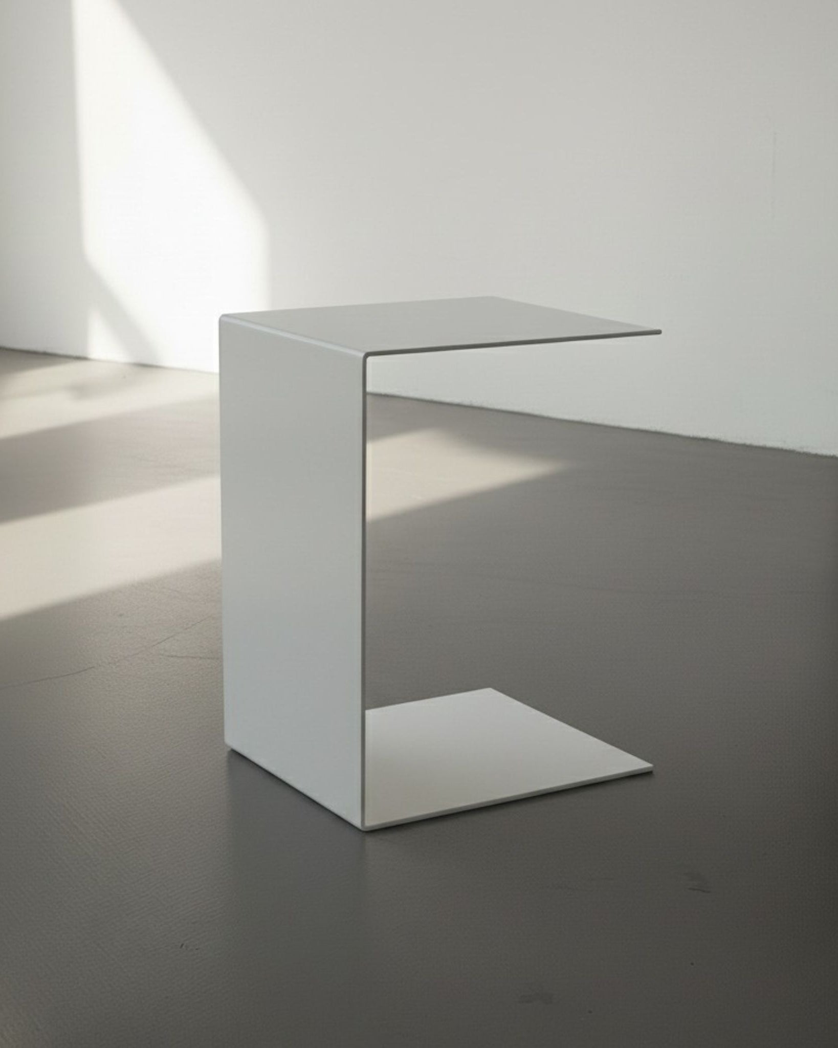 BIG C in weiß auf grauen Betonboden vor weißer Wand und Lichtspiel