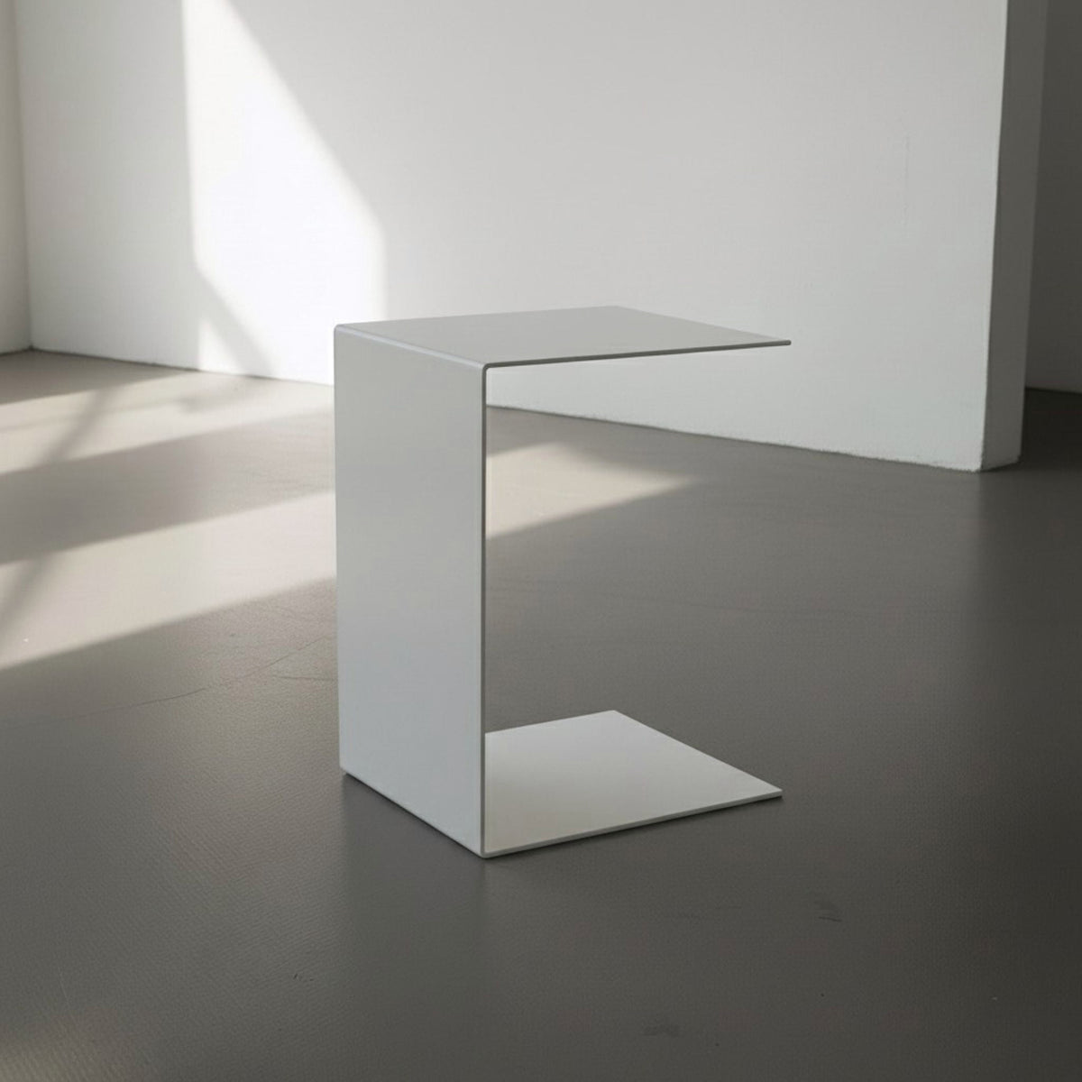 BIG C in weiß auf grauen Betonboden vor weißer Wand und Lichtspiel