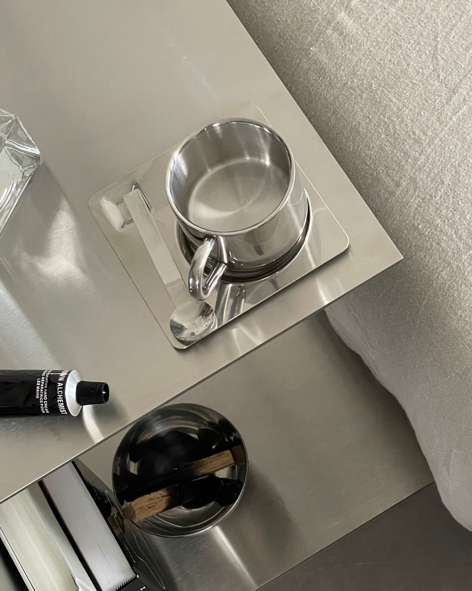 Beistelltisch aus gebürstetem Edelstahl mit Tasse und Deko-Elementen im modernen Wohnambiente