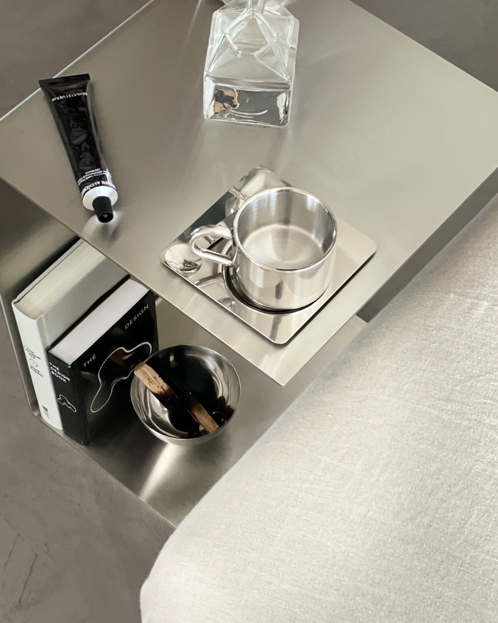 Beistelltisch aus gebürstetem Edelstahl mit Tasse, Deko und Büchern im stilvollen Wohnbereich