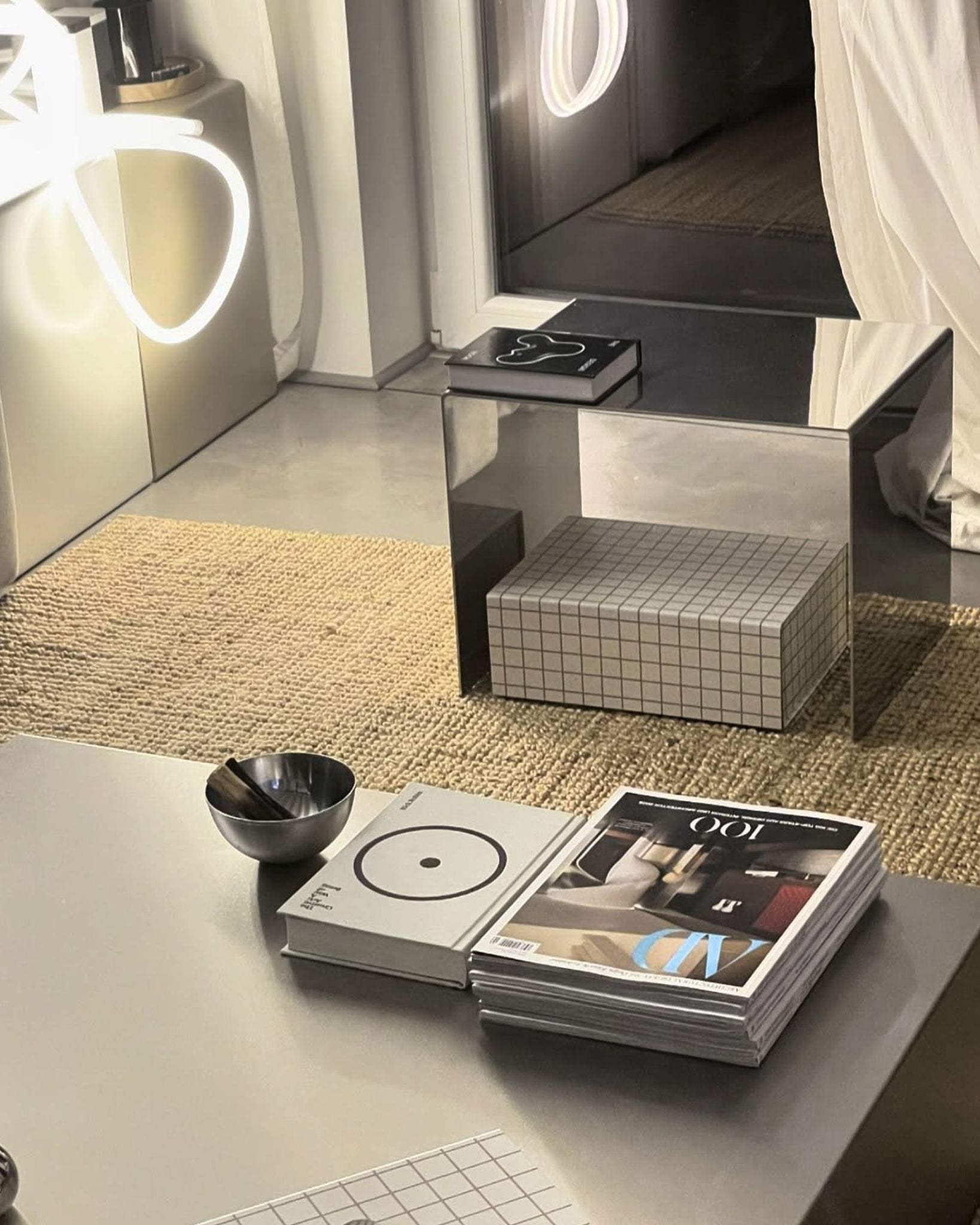 Spiegelpolierter Beistelltisch neben einem Couchtisch aus Edelstahl in einem stilvollen Wohnzimmer-Setting mit dekorativen Elementen