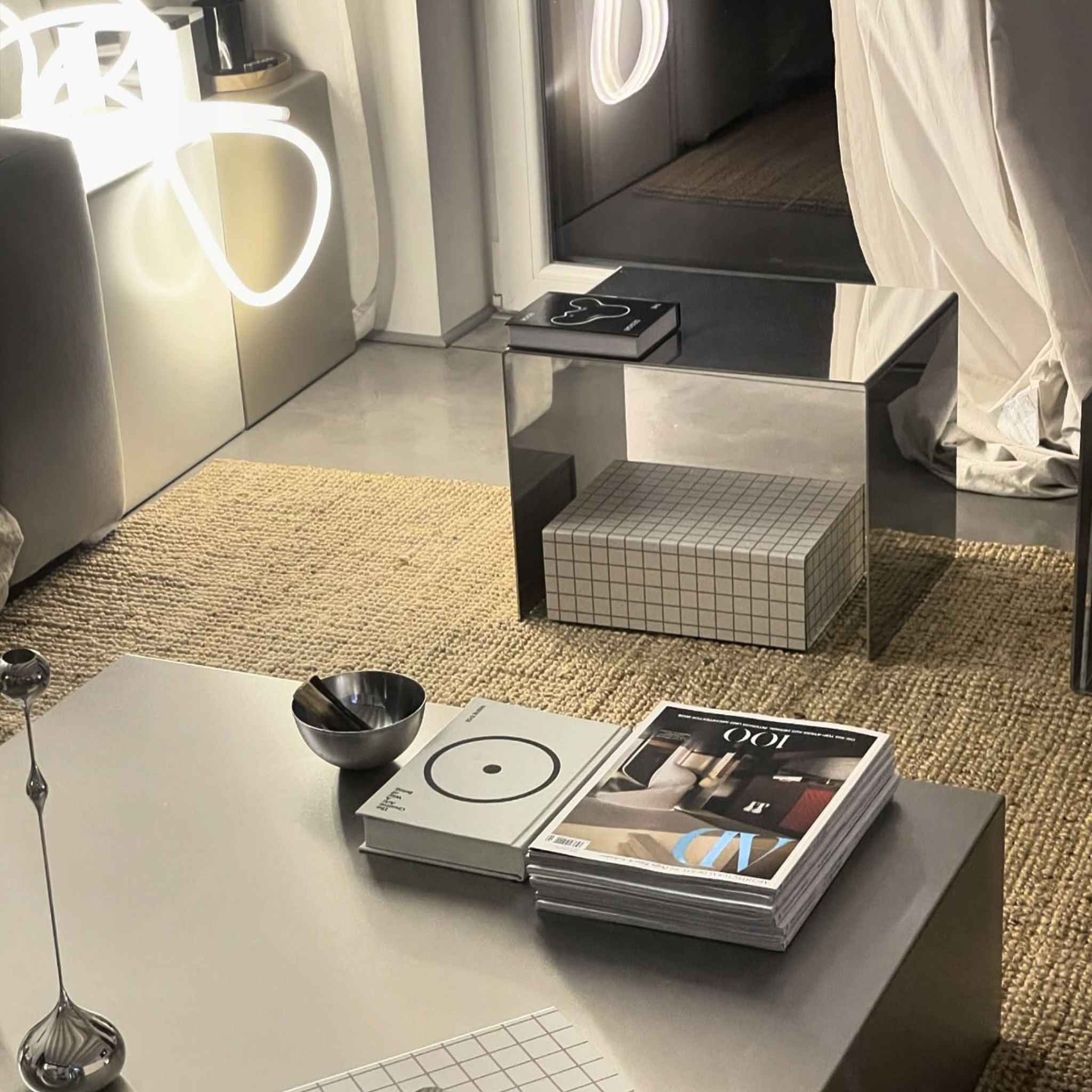 Spiegelpolierter Beistelltisch neben einem Couchtisch aus Edelstahl in einem stilvollen Wohnzimmer-Setting mit dekorativen Elementen