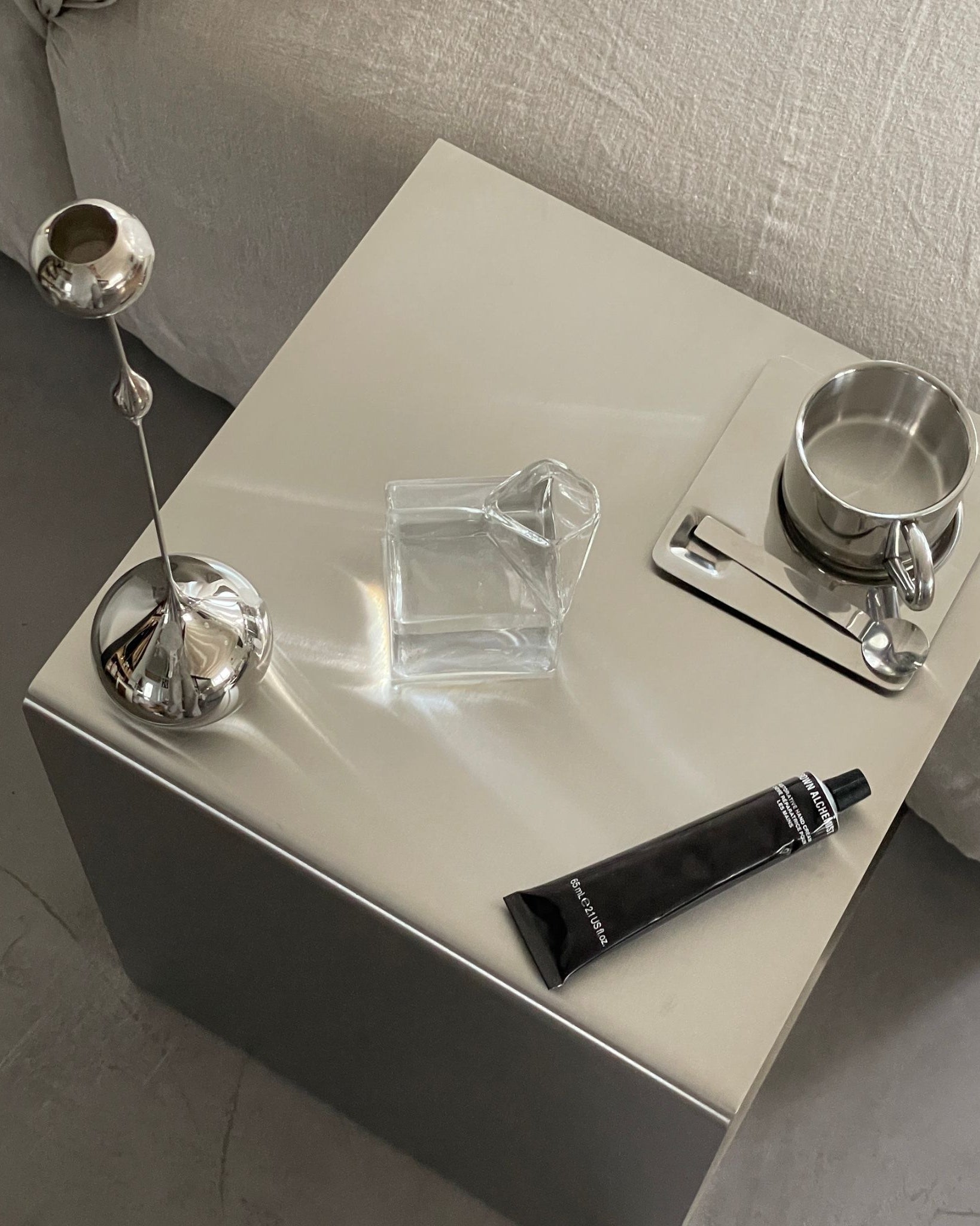 Eleganter Beistelltisch aus gebürstetem Edelstahl mit Glasvase, Teetasse und Design-Accessoires