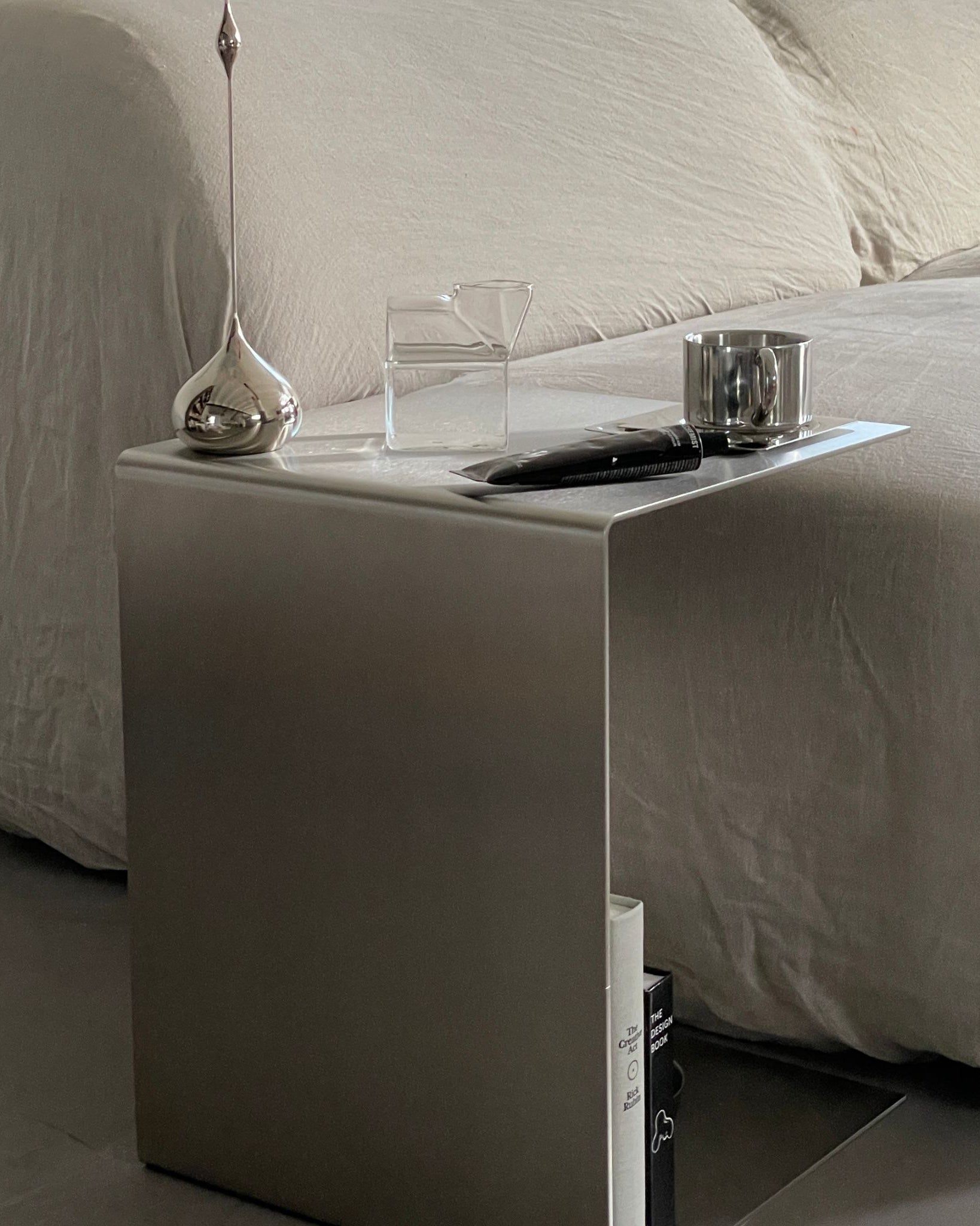 Moderner Beistelltisch aus gebürstetem Edelstahl mit stilvollen Accessoires neben einem Sofa