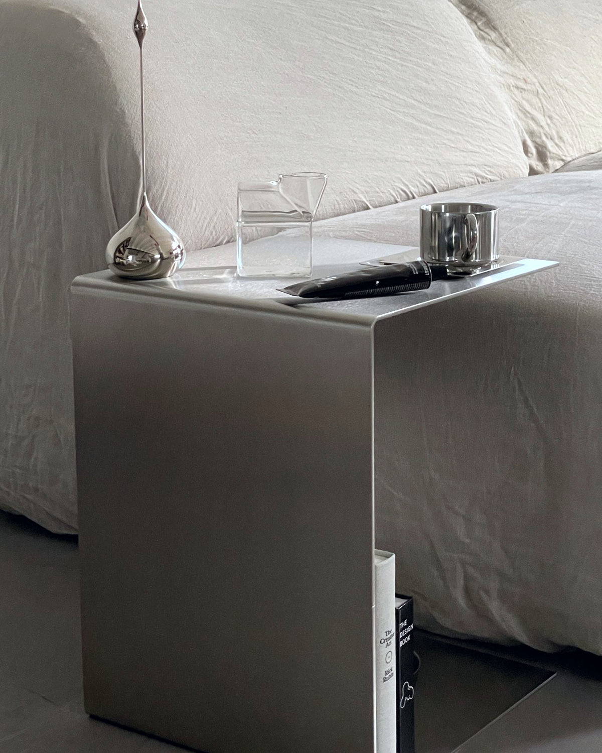 Moderner Beistelltisch aus gebürstetem Edelstahl mit stilvollen Accessoires neben einem Sofa