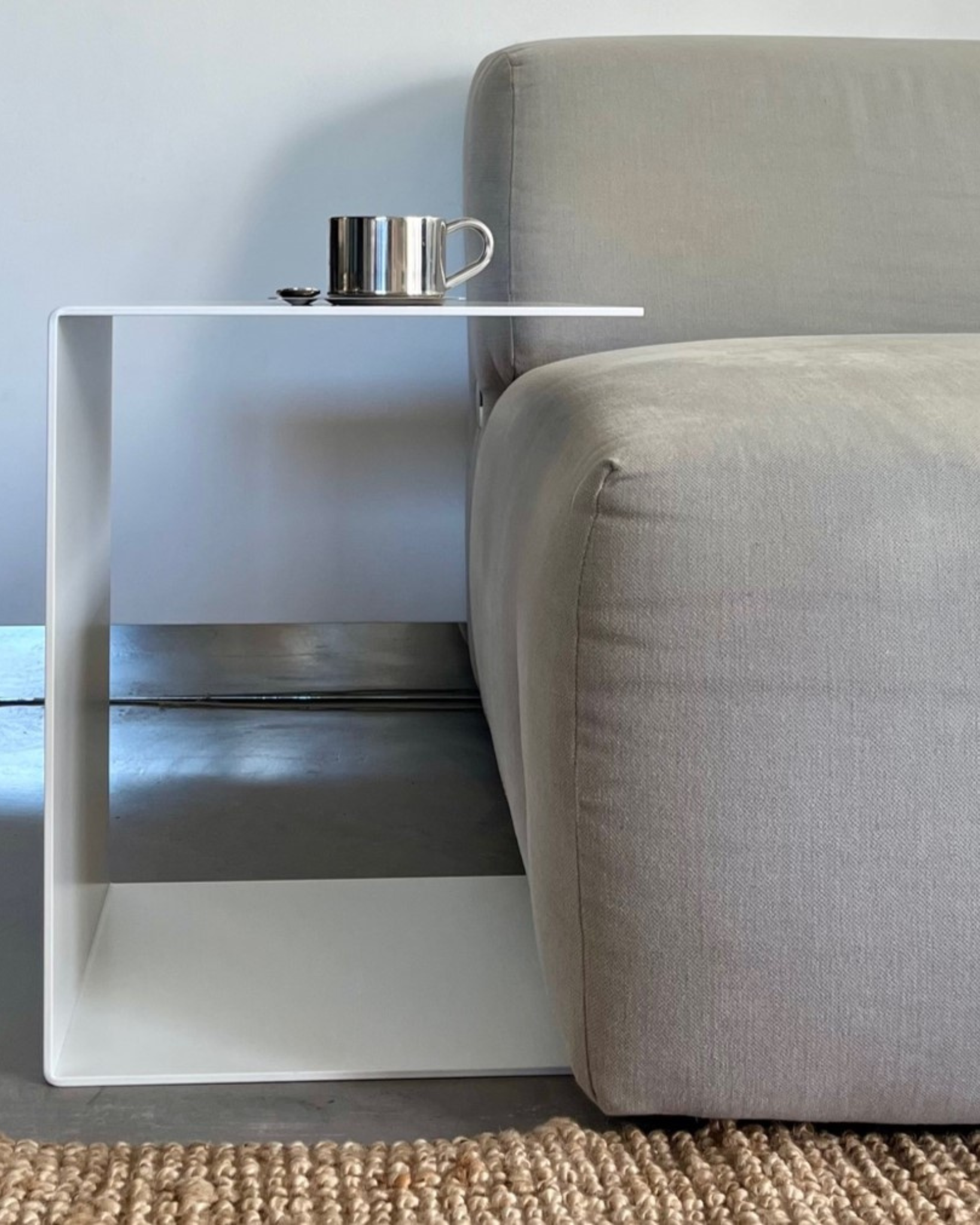 großer weißer Beistelltisch im Wohnzimmer neben grauer Couch