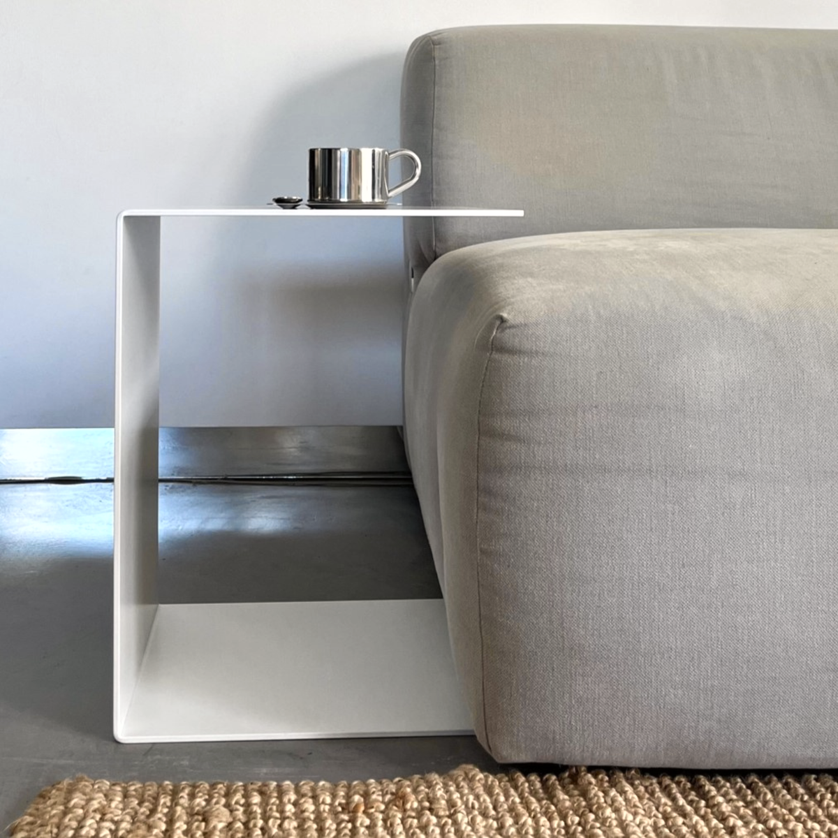 großer weißer Beistelltisch im Wohnzimmer neben grauer Couch