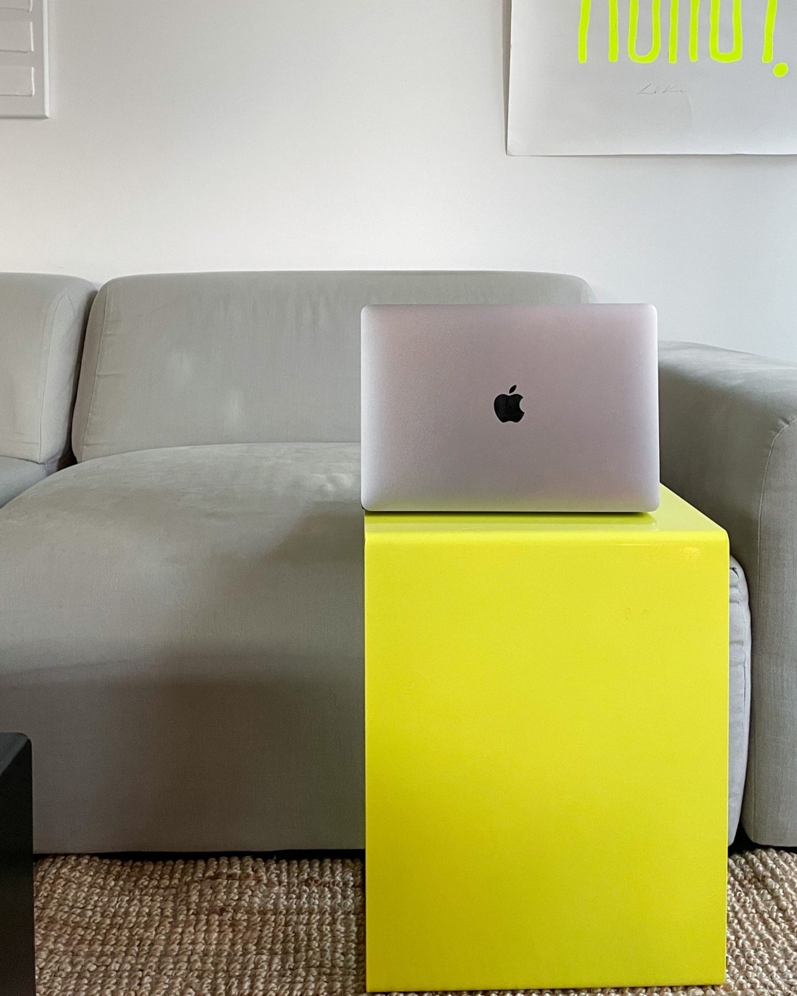 Gelber Beistelltisch mit MacBook vor grauem Sofa in modernem Wohnzimmer