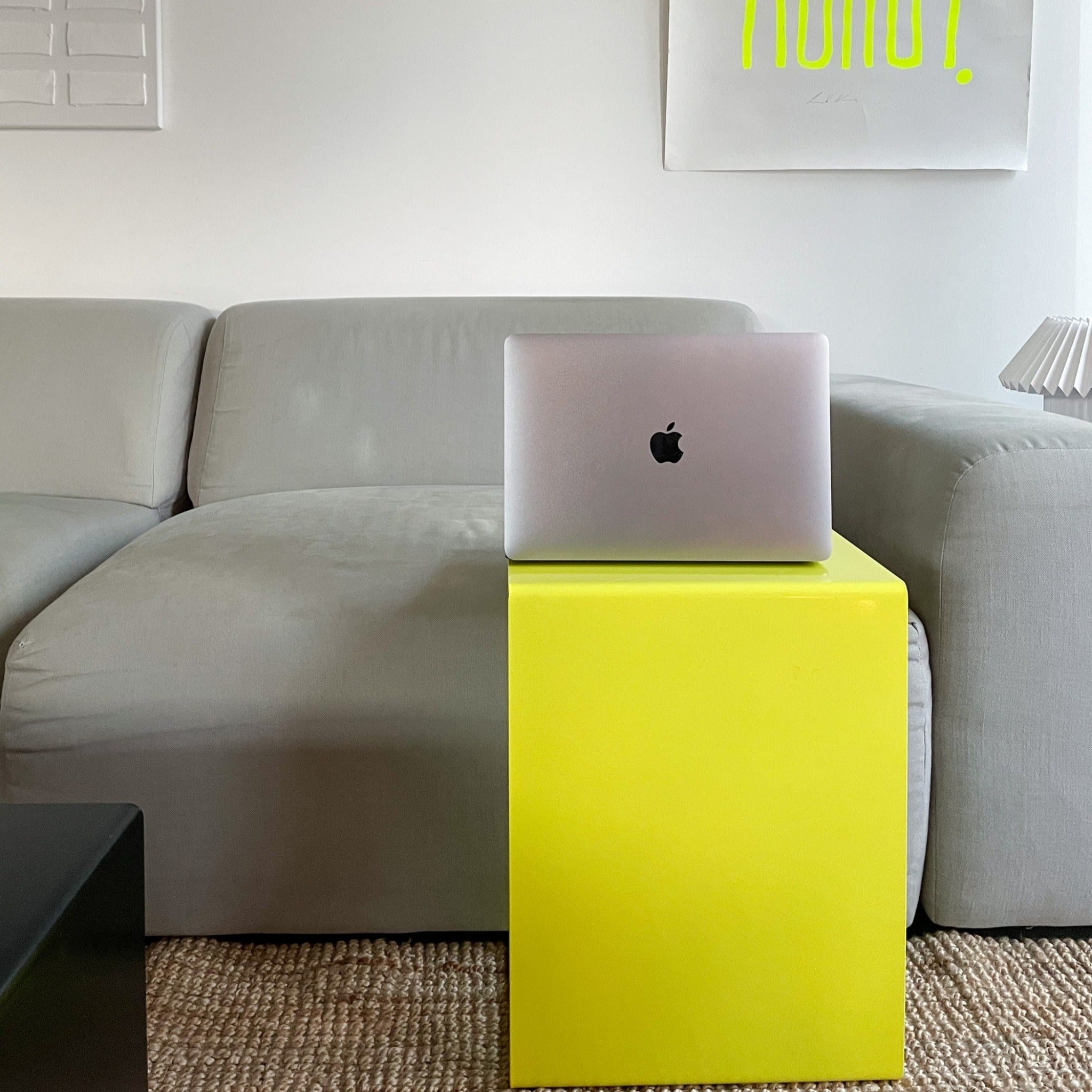 Gelber Beistelltisch mit MacBook vor grauem Sofa in modernem Wohnzimmer
