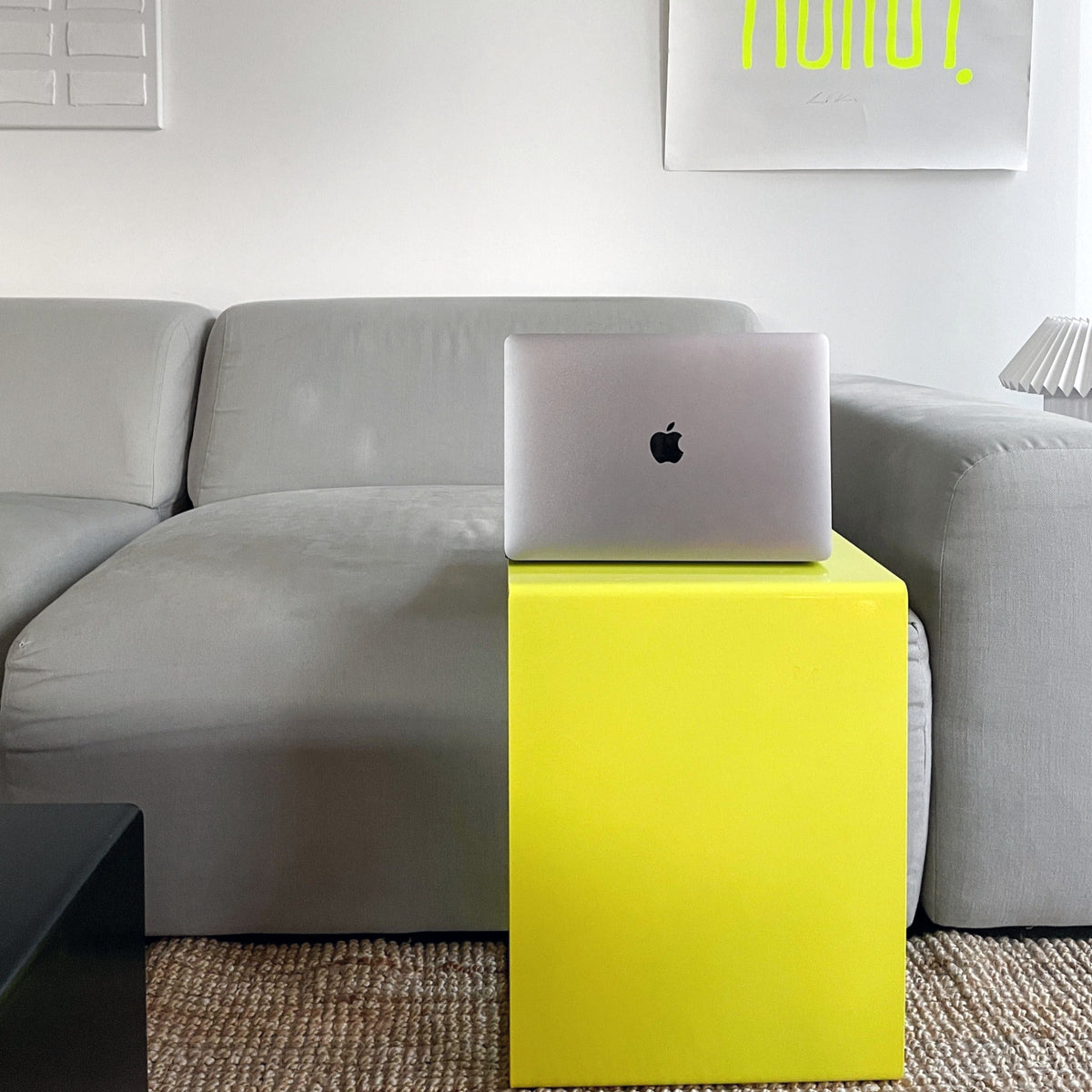 Gelber Beistelltisch mit MacBook vor grauem Sofa in modernem Wohnzimmer
