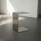 Brushed C aus Edelstahl gebürstet auf grauen Betonboden vor weißer Wand und Lichtspiel