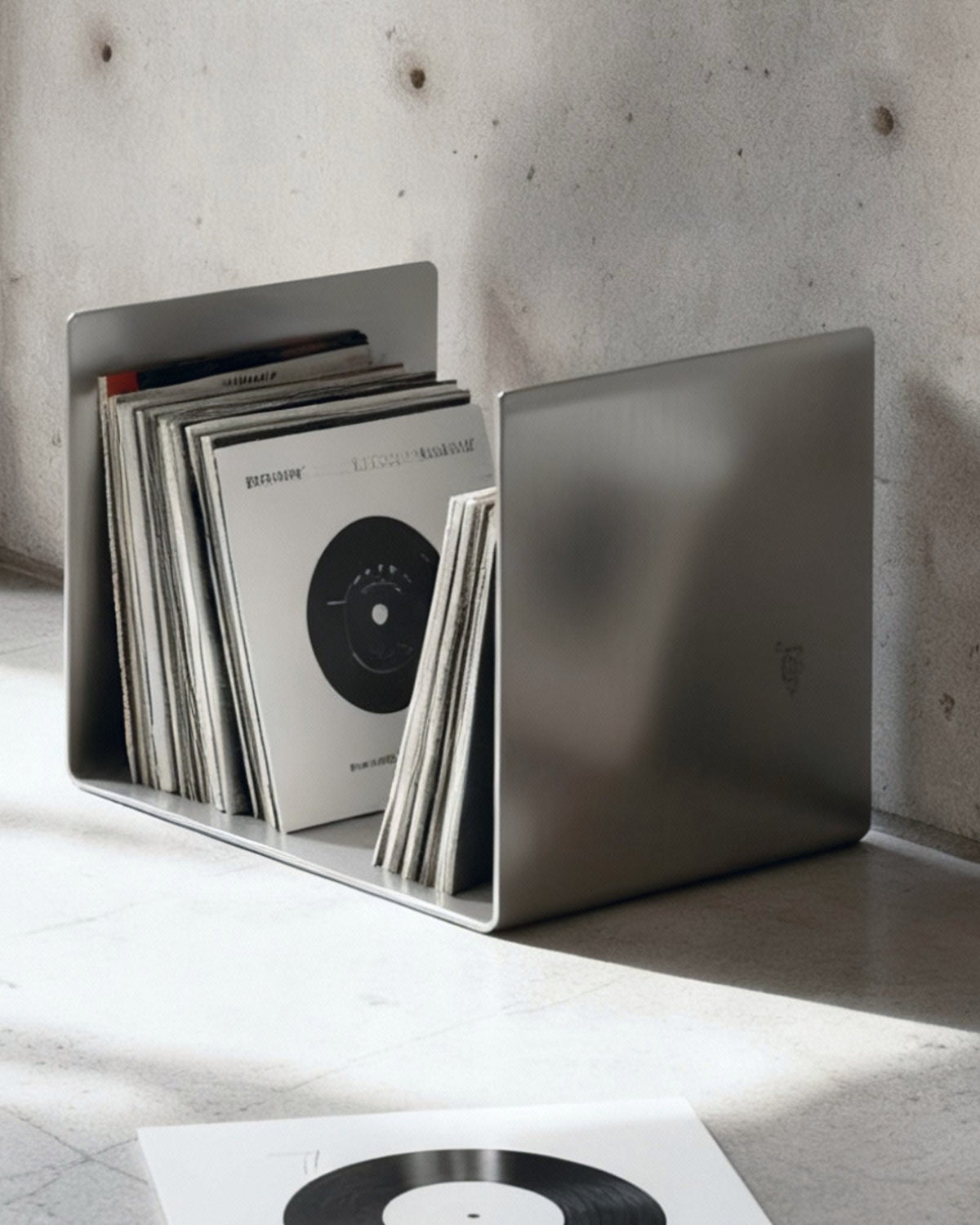 Brushed C Beistelltisch aus gebürstetem Edelstahl als stilvolle Vinylablage in modernem Betoninterior