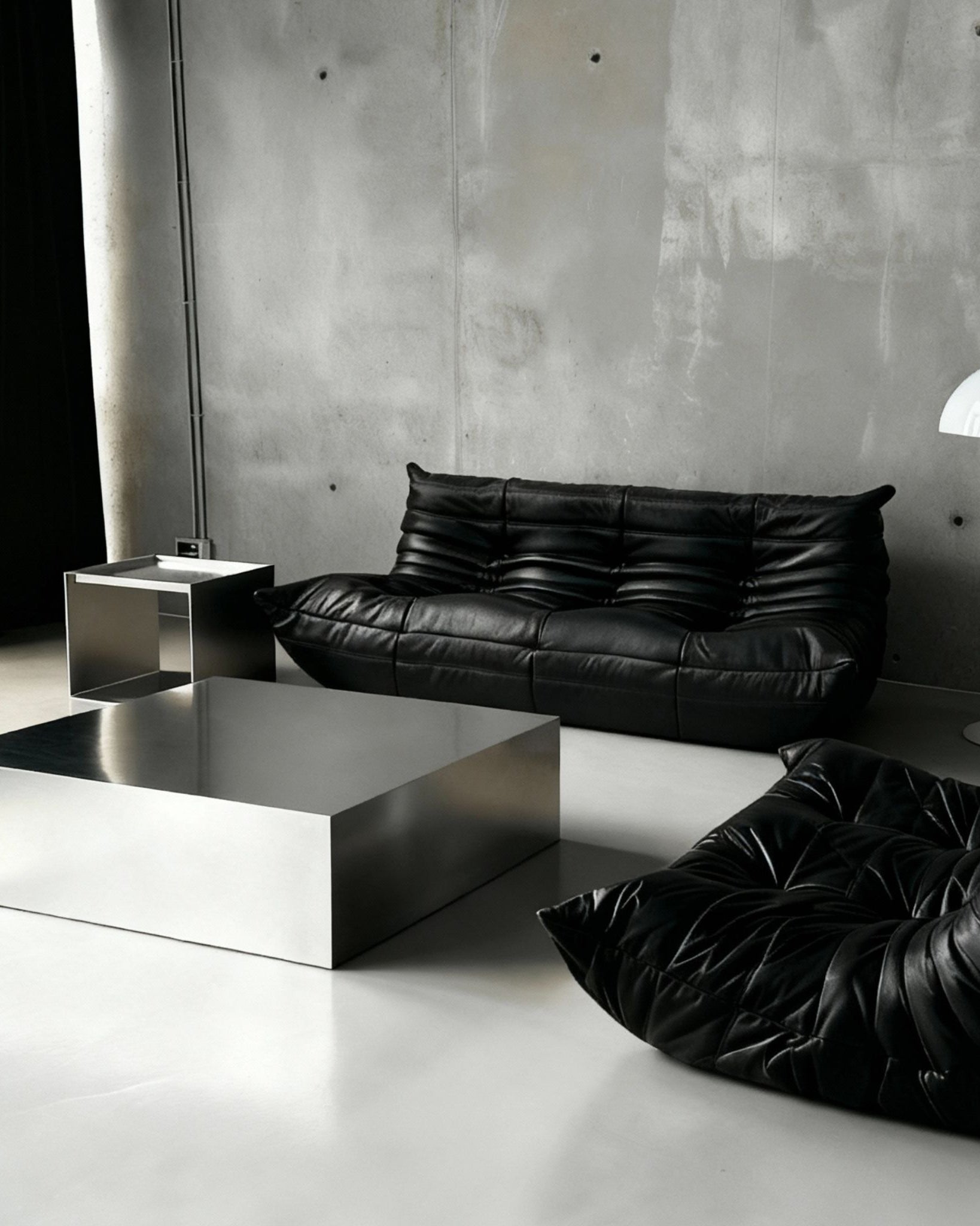 Brushed Q vor Betonwand auf Betonboden mit schwarzem lignet rose Sofa aus Leder