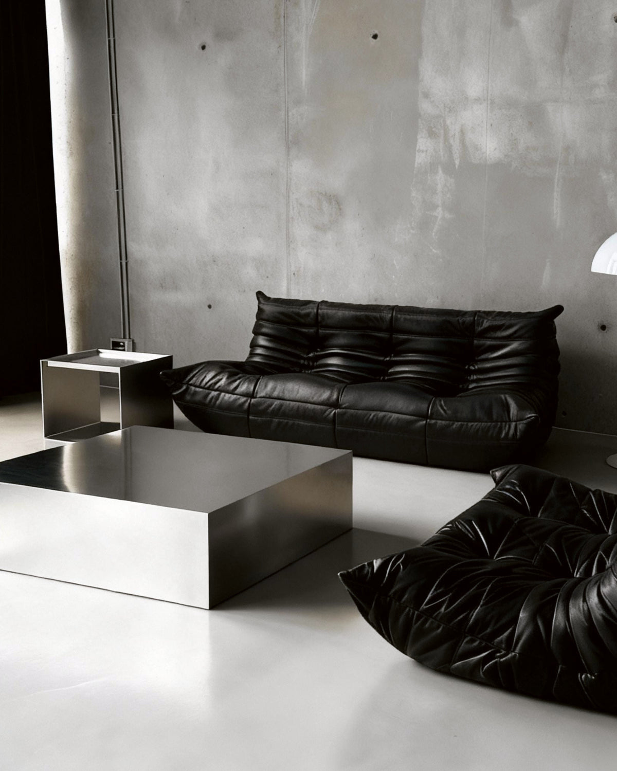 Brushed Q vor Betonwand auf Betonboden mit schwarzem lignet rose Sofa aus Leder