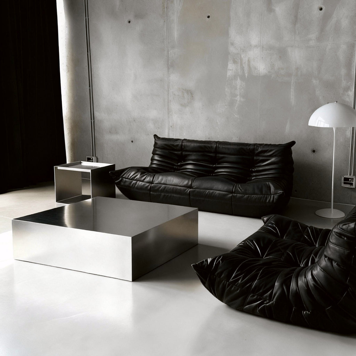 Brushed Q vor Betonwand auf Betonboden mit schwarzem lignet rose Sofa aus Leder