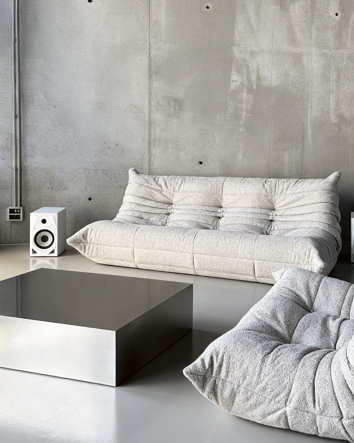 Brushed Q vor Betonwand auf Betonboden mit weissem lignet rose Sofa