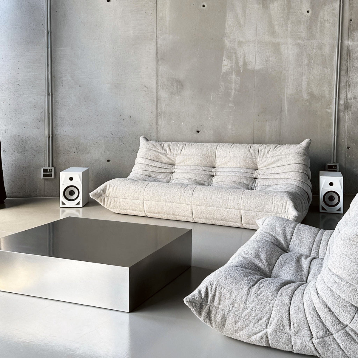 Brushed Q vor Betonwand auf Betonboden mit weissem lignet rose Sofa