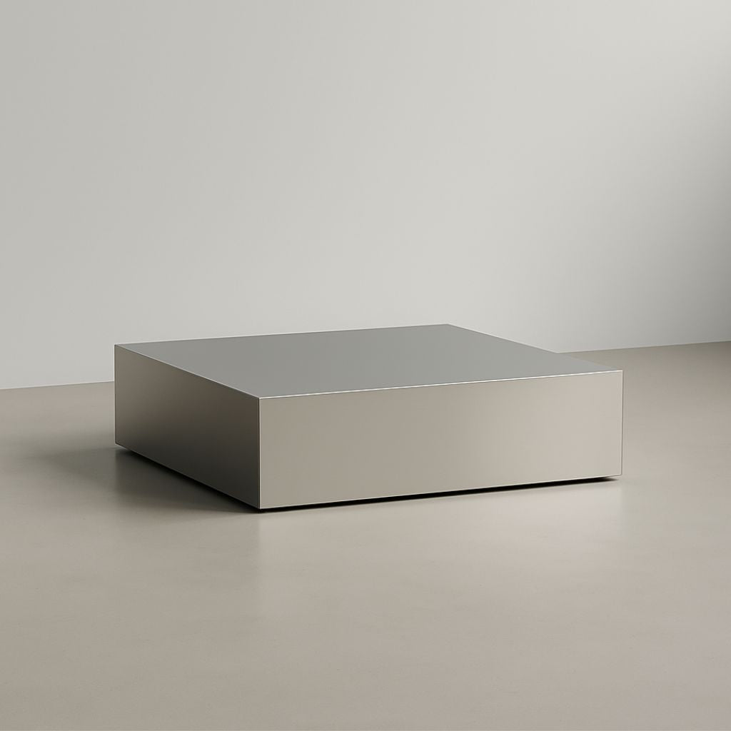 Minimalistischer Couchtisch Brushed Q aus gebürstetem Edelstahl in kubischer Form auf hellem Boden vor grauer Wand