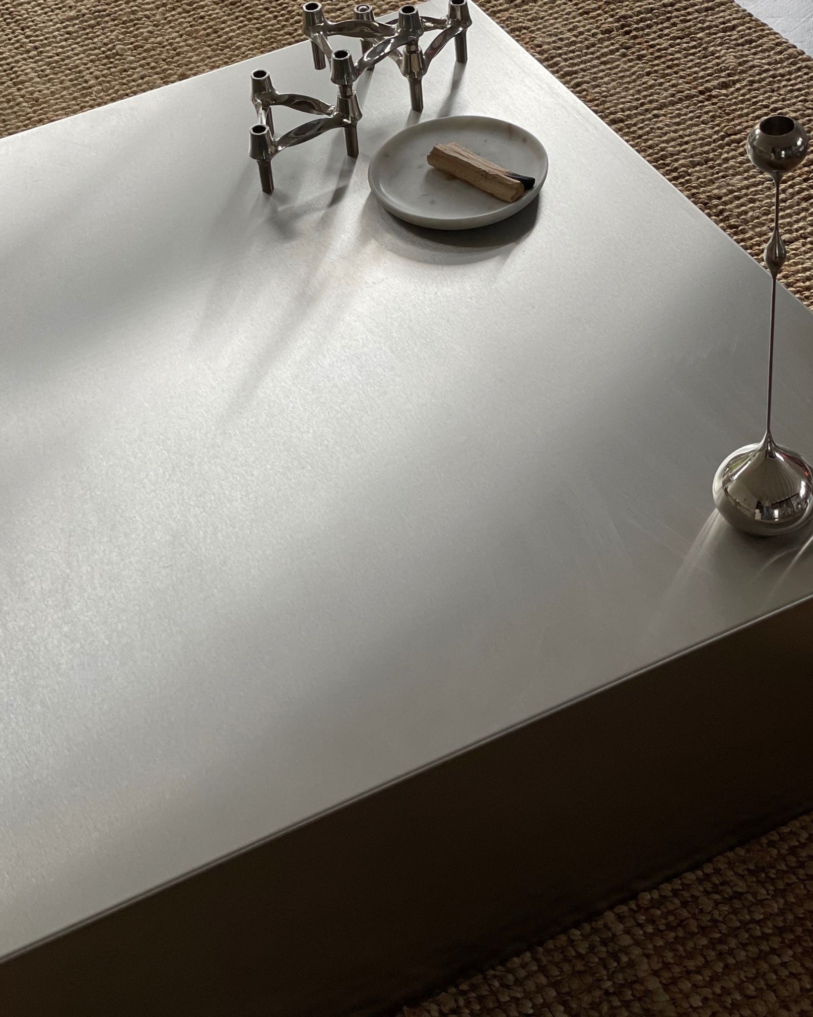 Detailaufnahme eines Couchtischs aus gebürstetem Edelstahl mit stilvoller Dekoration und natürlichem Lichteinfall