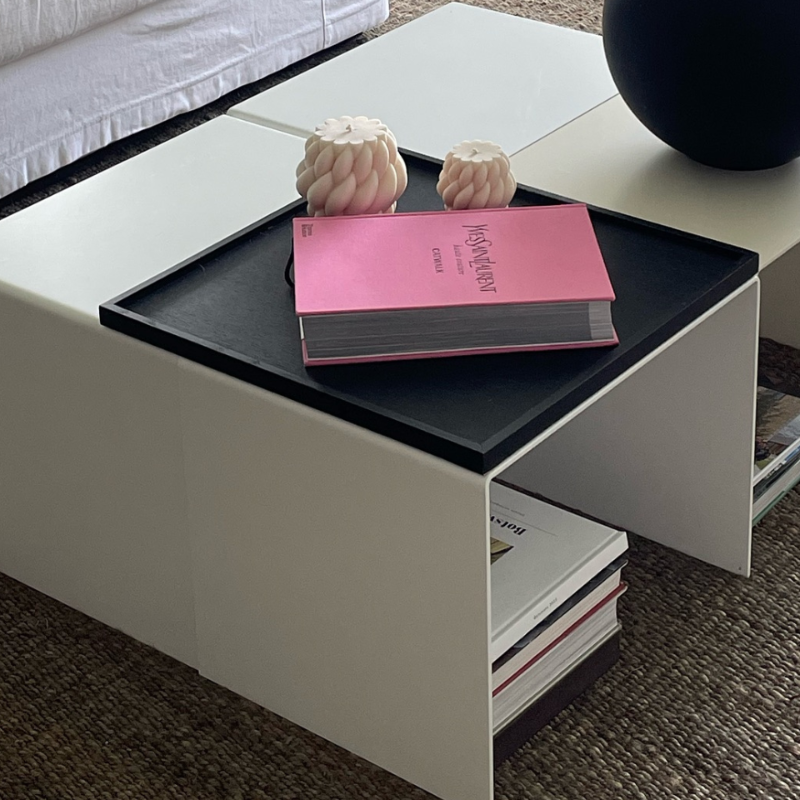 Moderner weißer Couchtisch mit integriertem Regal, dekoriert mit schwarzer Vase, Designbuch und Kerzen in einem stilvollen Wohnzimmer
