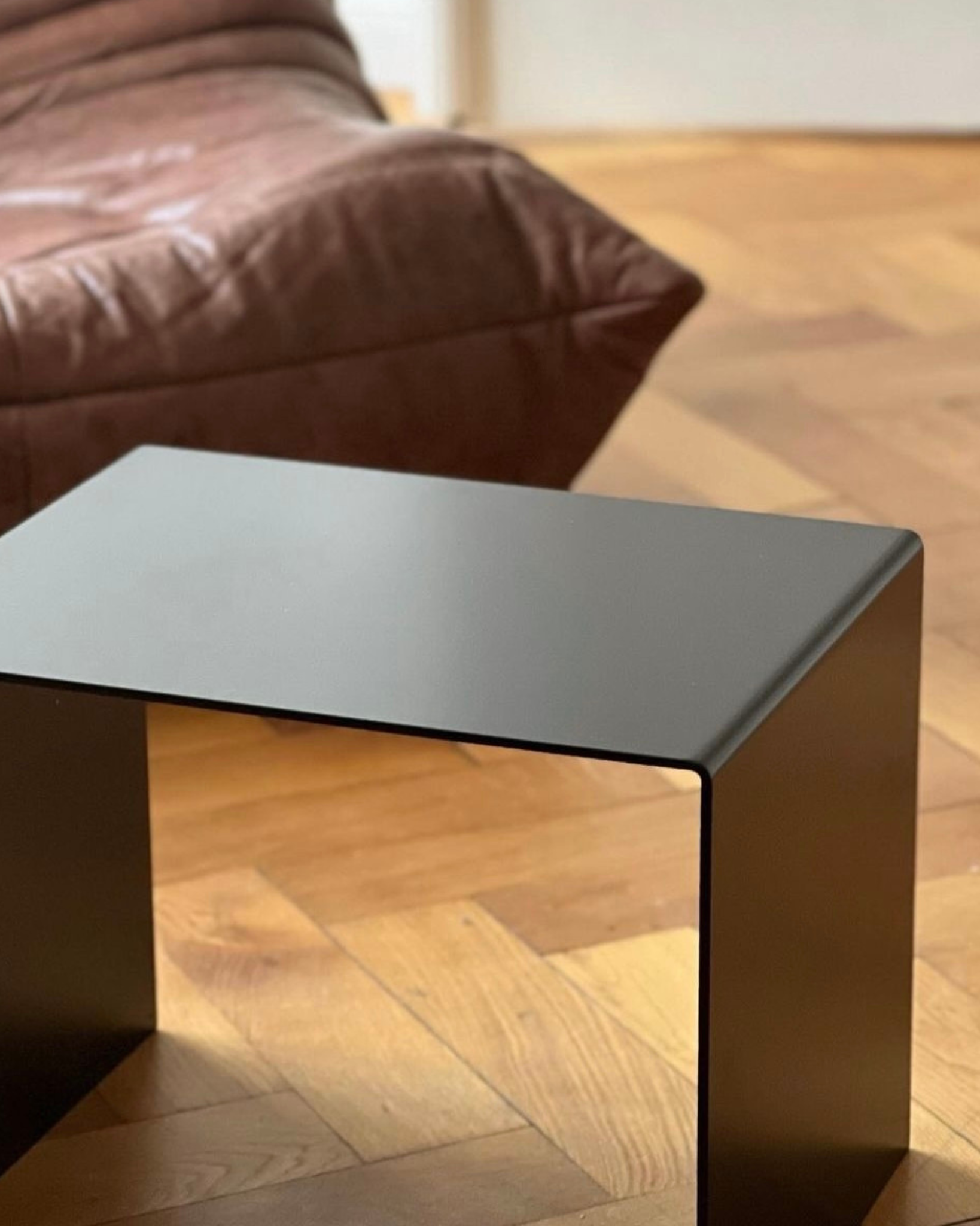 Schwarzer minimalistischer Beistelltisch aus Metall auf Parkettboden, modernes Wohnzimmerdesign