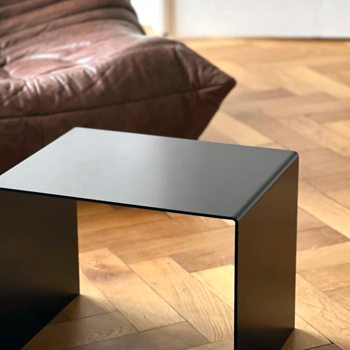 Schwarzer minimalistischer Beistelltisch aus Metall auf Parkettboden, modernes Wohnzimmerdesign