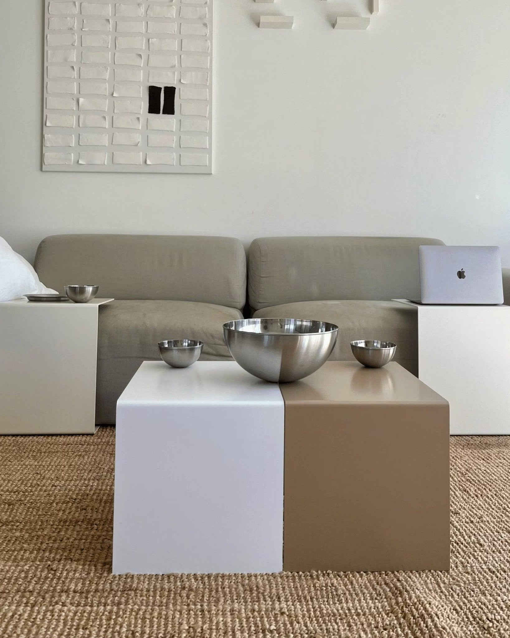 Zweifarbiger Couchtisch in Weiß und Graubeige mit Edelstahl-Schalen, kombiniert mit passenden Beistelltischen vor einem beigen Sofa