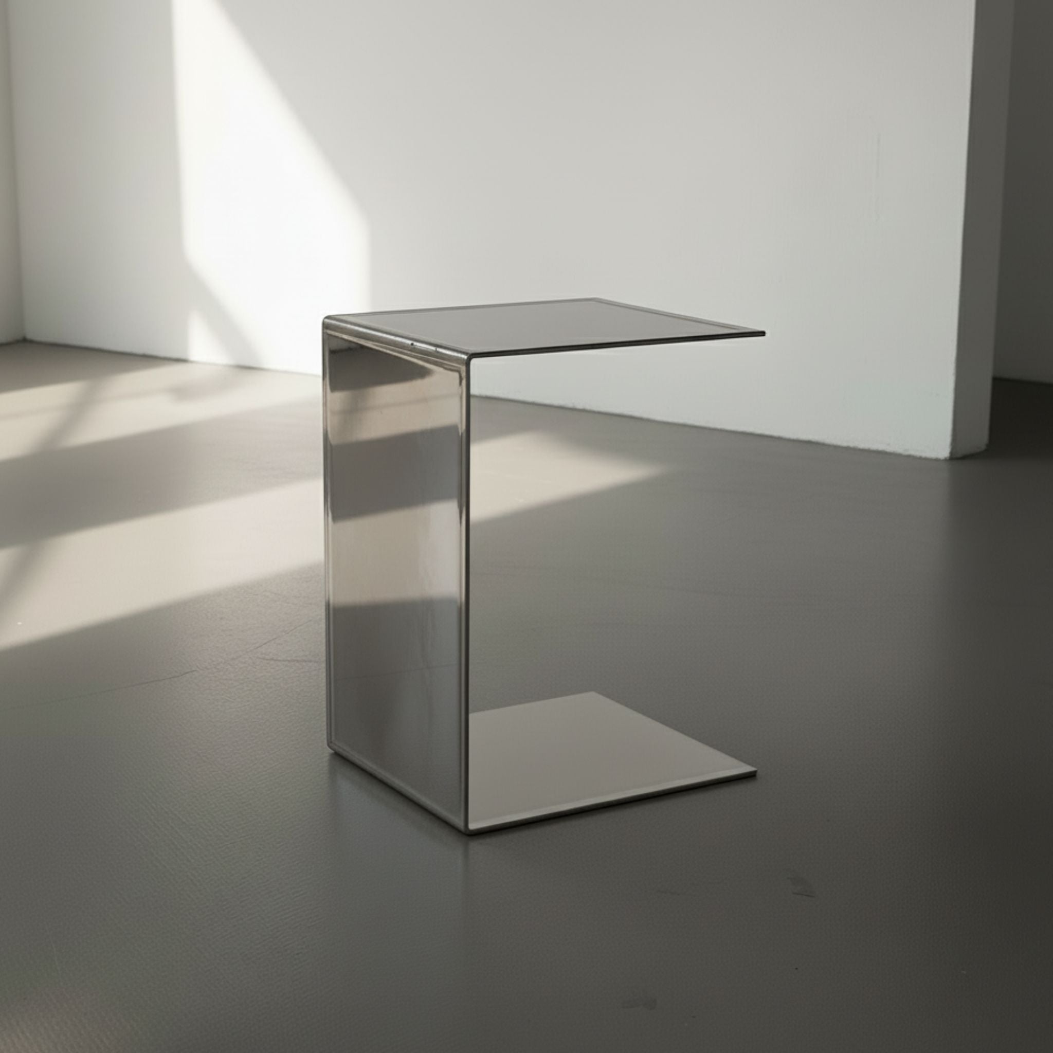 Mirror aus spiegelpoliertem Edelstahl auf grauen Betonboden vor weißer Wand und Lichtspiel