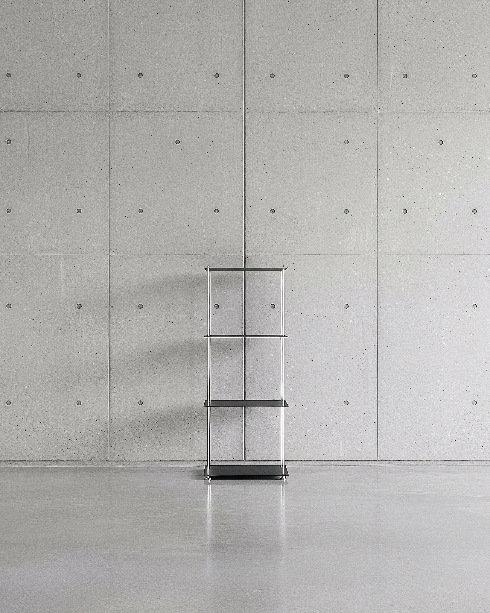 Modulum mit 4 Fachböden in schwarz ultramatt auf grauen Betonboden vor grauer Betonwand mit Löchern