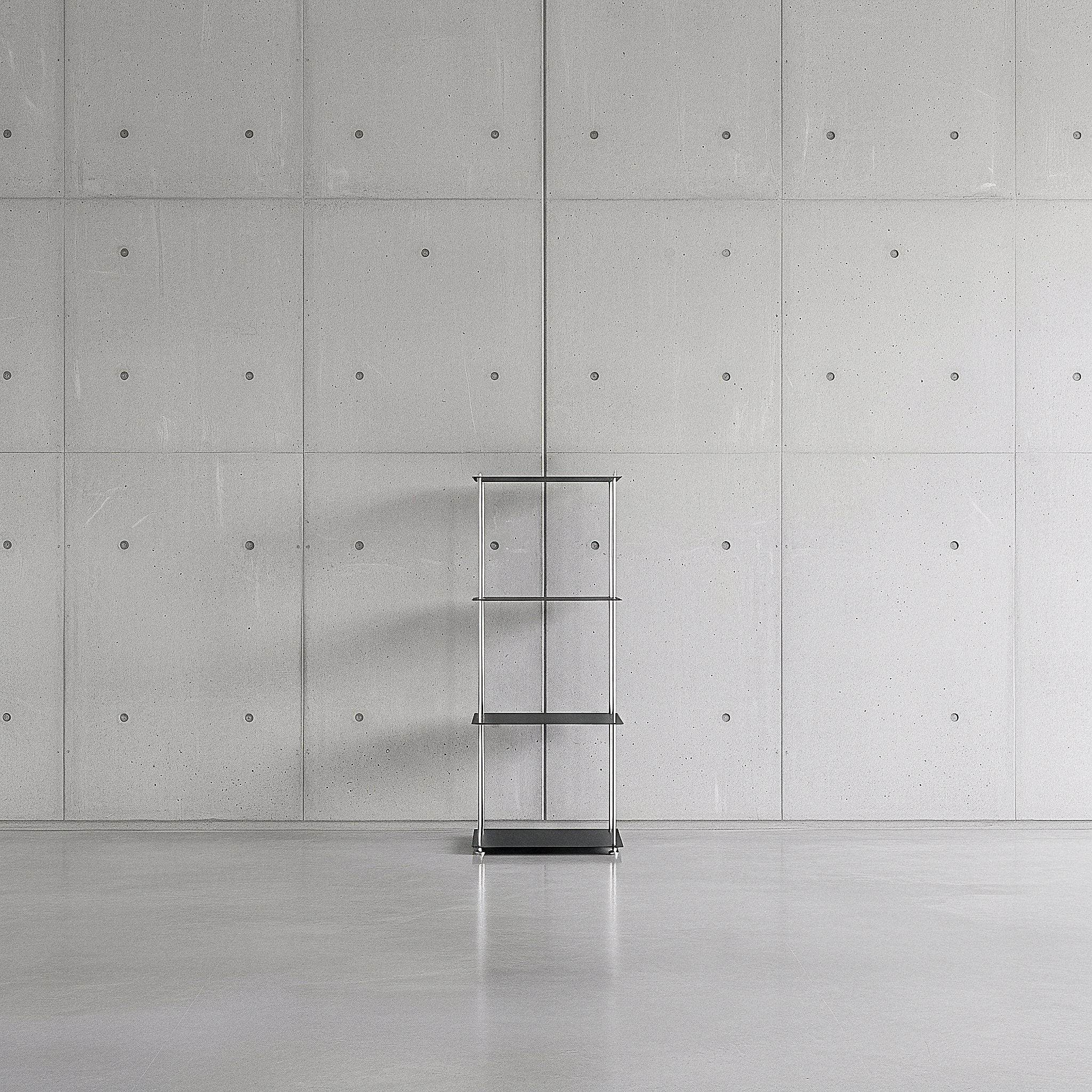 Modulum mit 4 Fachböden in schwarz ultramatt auf grauen Betonboden vor grauer Betonwand mit Löchern