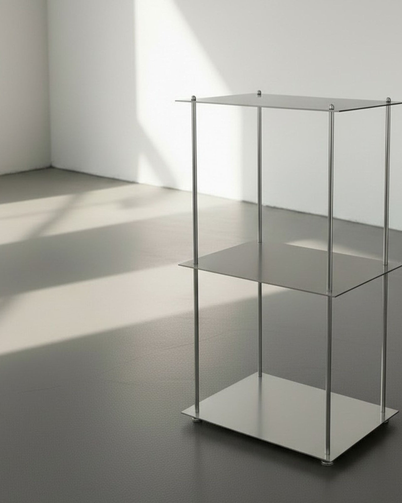 Modulum mit 3 Fachböden aus gebürstetem Edelstahl auf grauen Betonboden vor weißer Wand und Lichtspiel