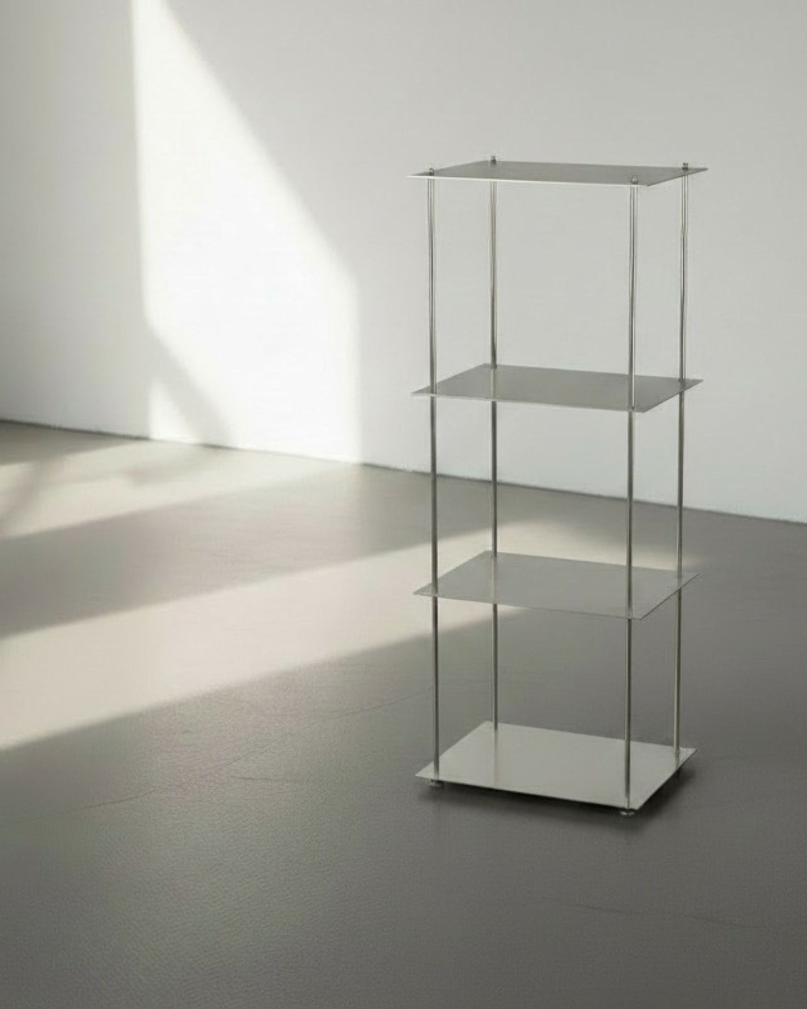 Modulum mit 4 Fachböden aus gebürstetem Edelstahl auf grauen Betonboden vor weißer Wand und Lichtspiel