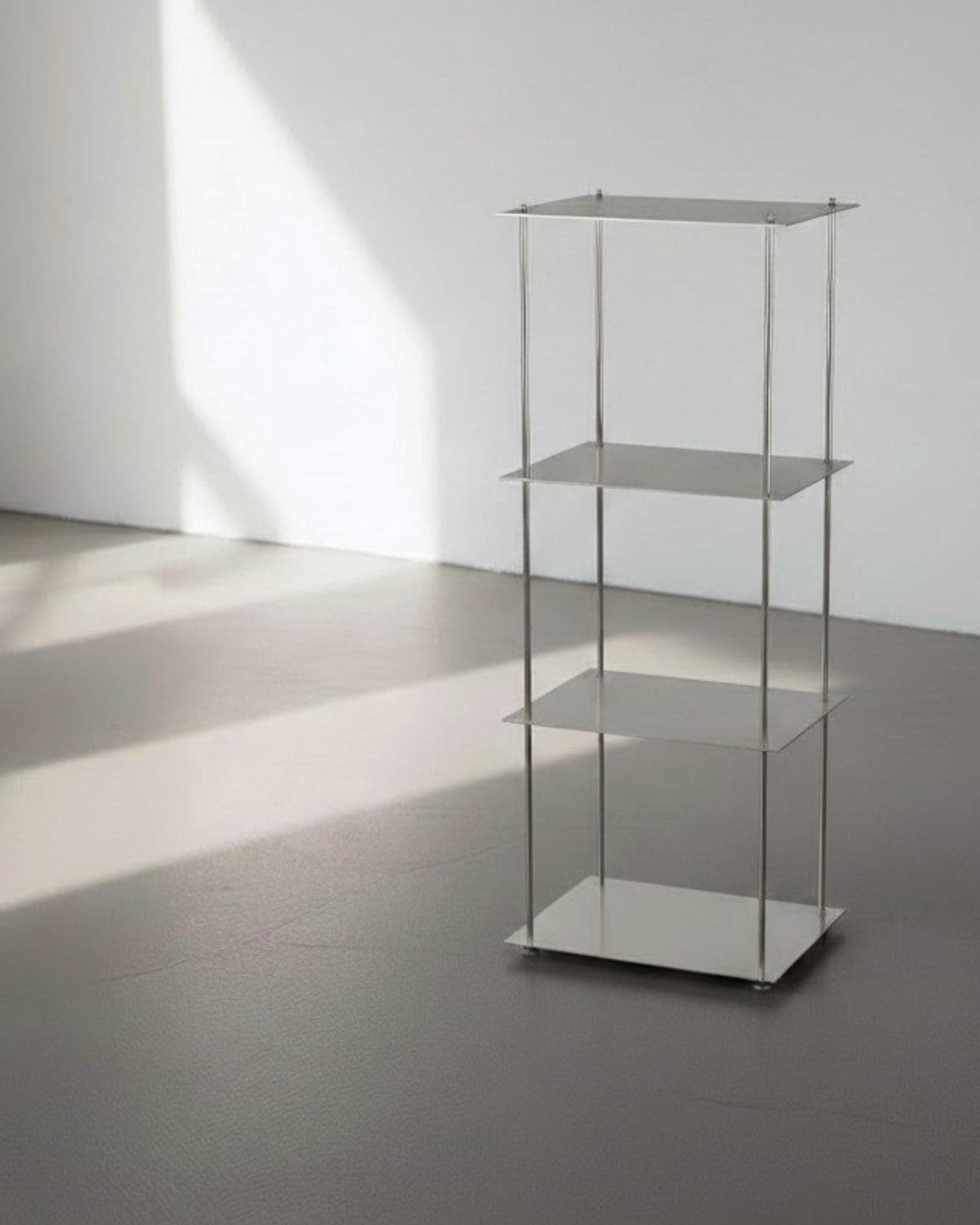 Modulum mit 4 Fachböden aus gebürstetem Edelstahl auf grauen Betonboden vor weißer Wand und Lichtspiel