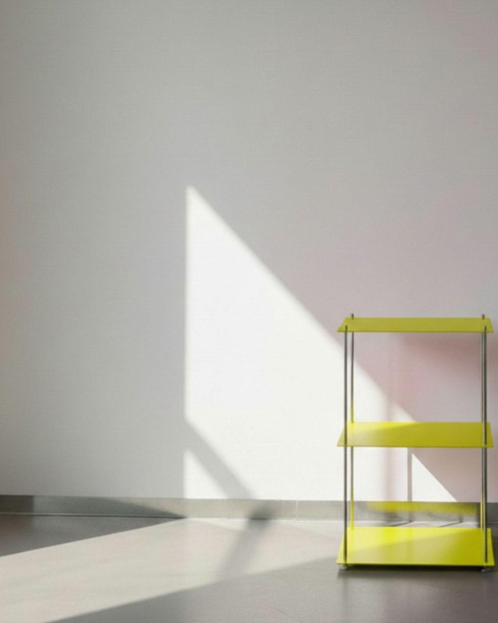 Modulum in leuchtgelb mit 3 Fachböden auf grauen Betonboden vor weißer Wand und Lichtspiel