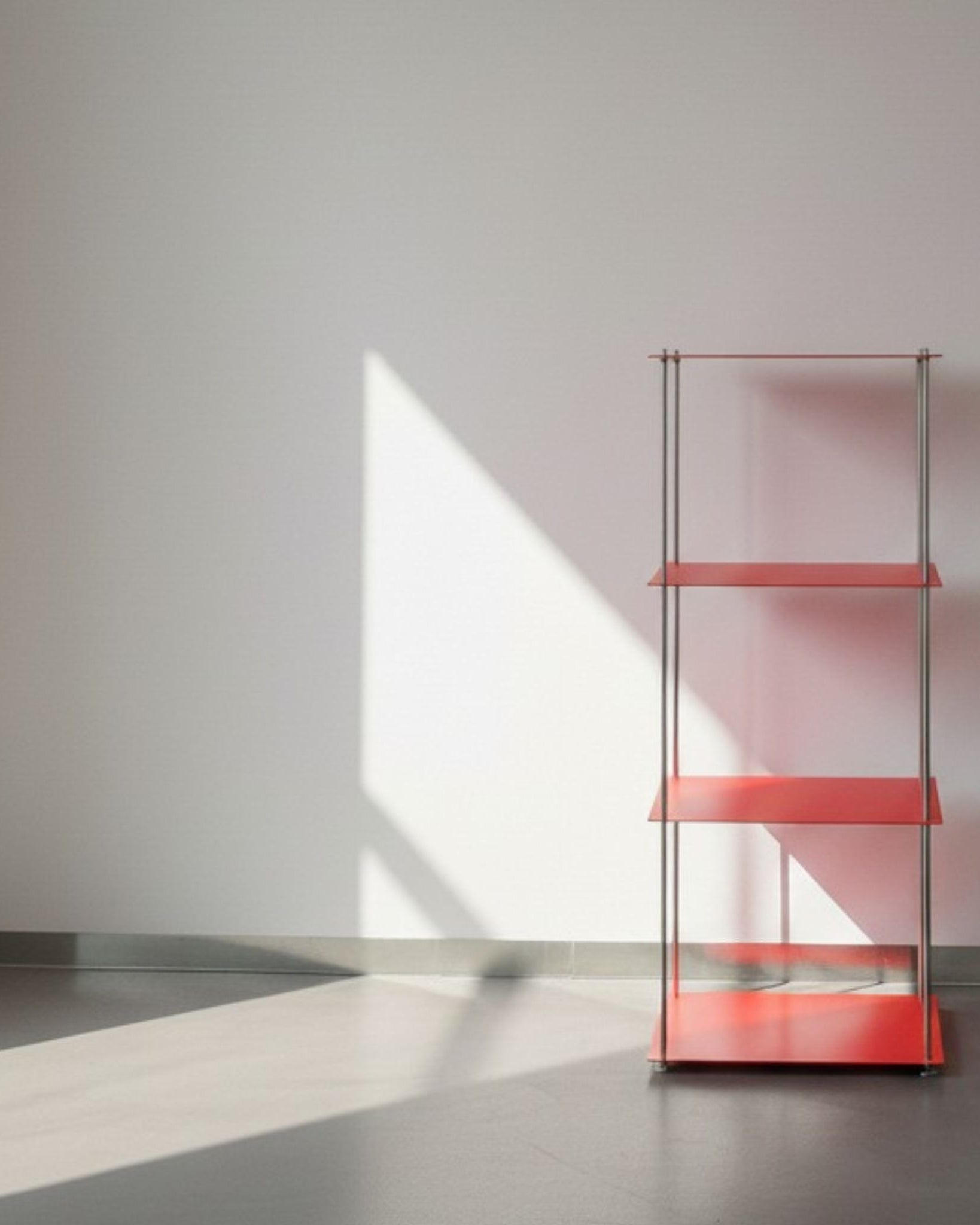 Modulum in leuchtrot mit 4 Fachböden auf grauen Betonboden vor weißer Wand und Lichtspiel