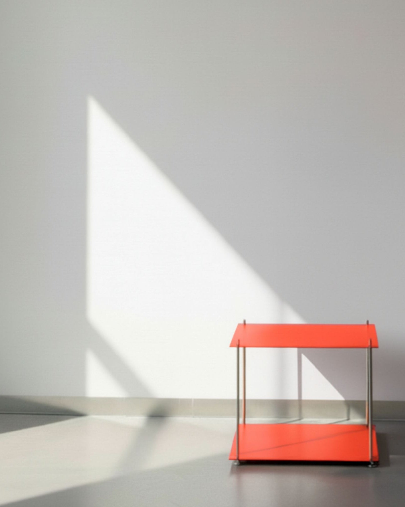 Modulum in leuchtrot mit Basismodul auf grauen Betonboden vor weißer Wand und Lichtspiel