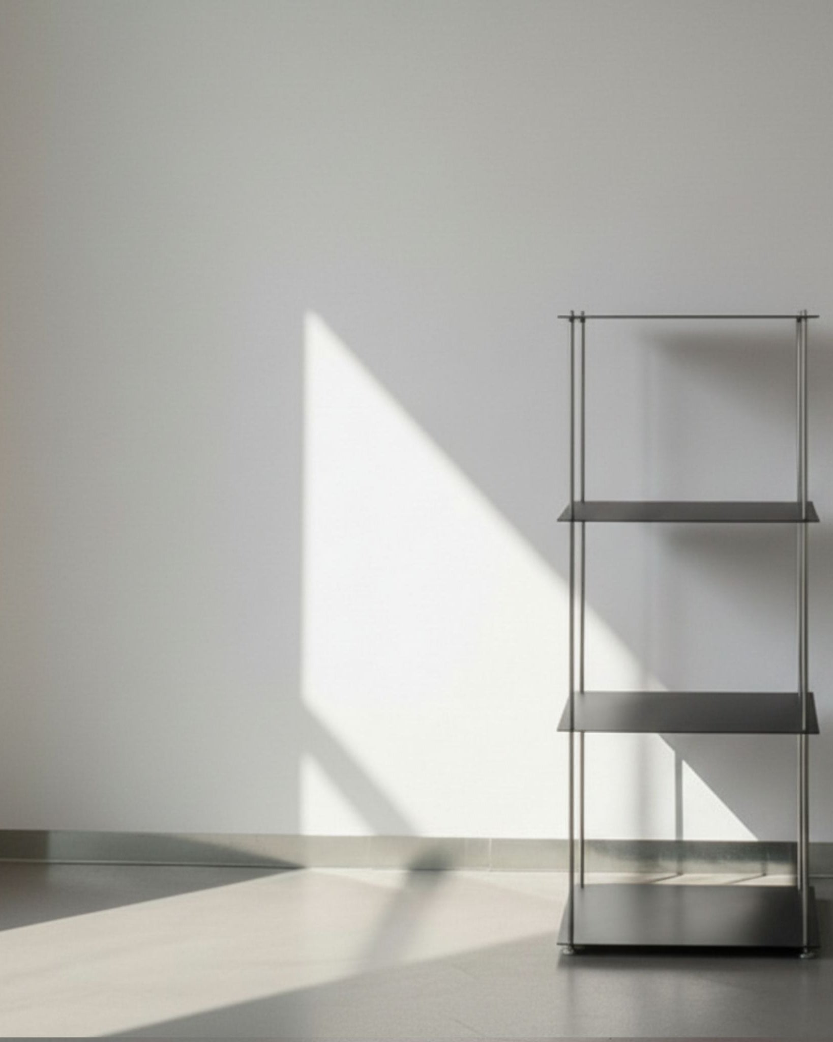 Modulum in schwarz ultramatt mit 4 Fachböden auf grauen Betonboden vor weißer Wand und Lichtspiel