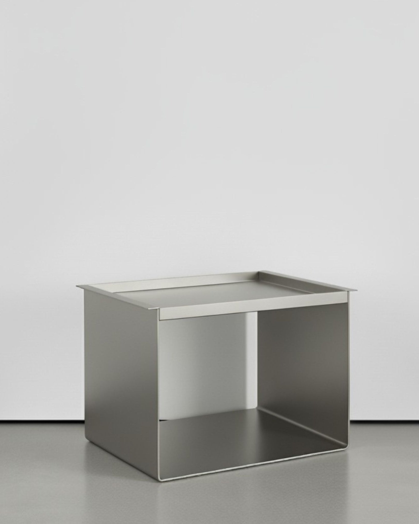 Tray Table Brushed C aus Edelstahl gebürstet auf grauen Betonboden vor weißer Wand und Lichtspiel