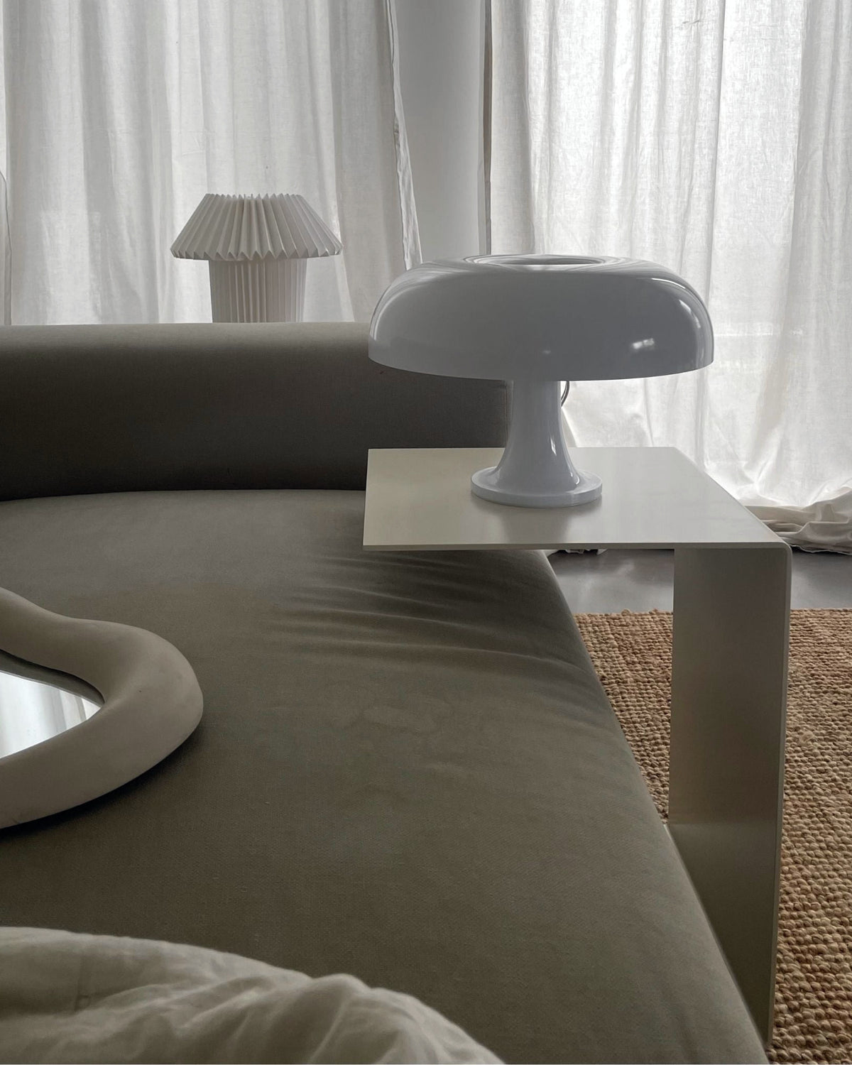 Cremeweißer Beistelltisch an Sofa mit Designerlampe und minimalistischem Wohnstil